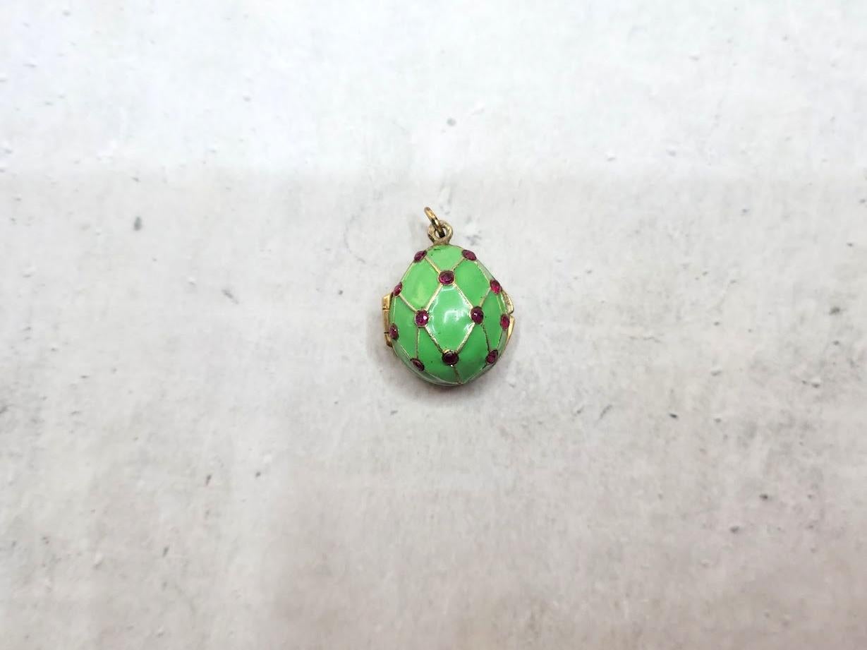 Presenting a stunning pendant designed in the shape of a Russian Imperial gilt silver and enamel egg. This exquisite piece showcases a relief image of the cobalt mesh with rubies adorned with gold and green emerald enamel. 
Believed to be a