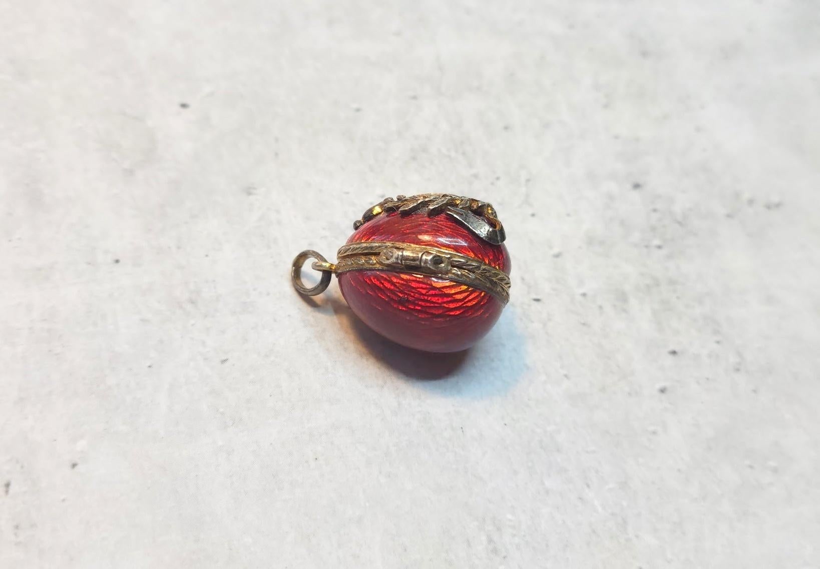Presenting a stunning locket-pendant designed in the shape of a Russian Imperial gilt silver and guilloche enamel egg. The body of the egg is enameled in a deep, beautiful red guilloche enamel. The repeating patterns of the enamel look like hundreds