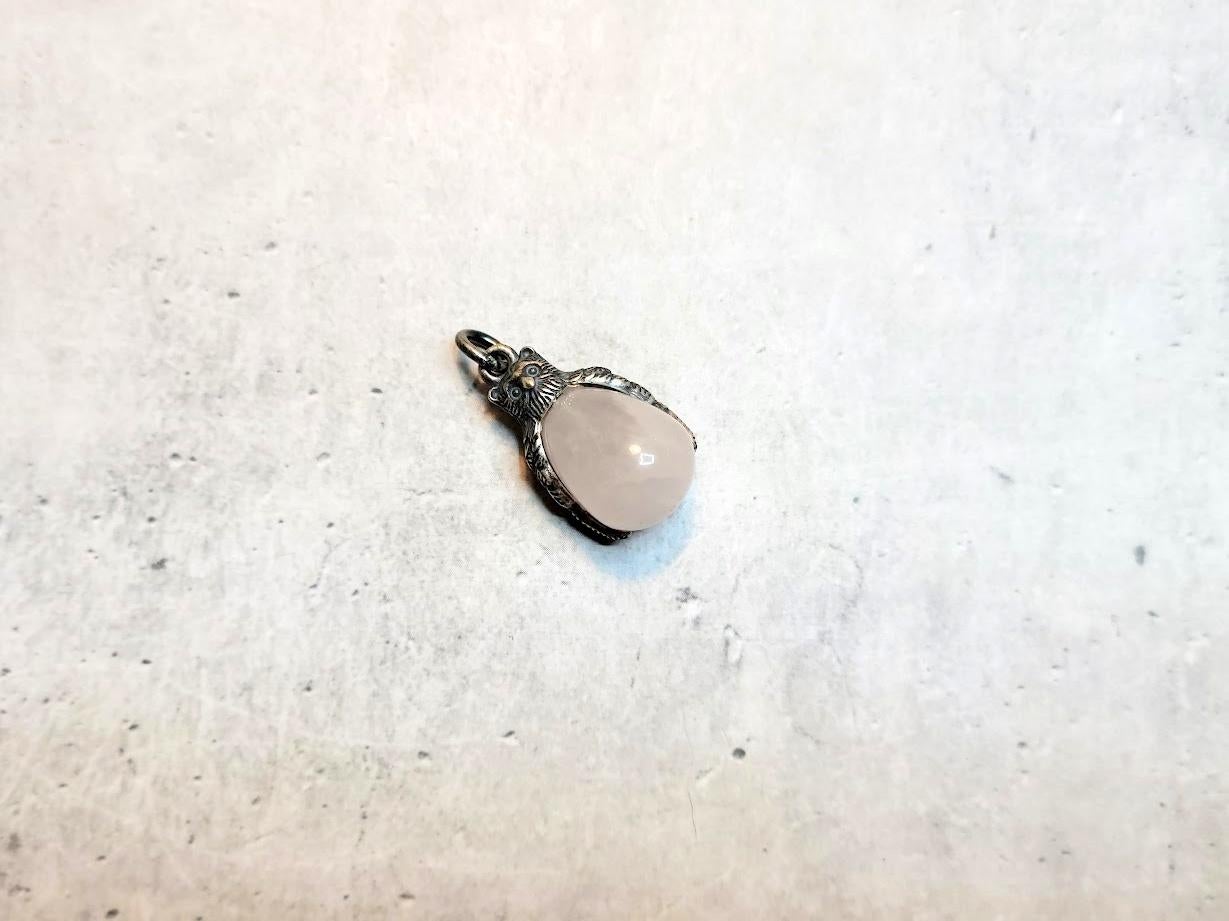 We present an adorable egg pendant in the form of a miniature silver owl with carved wings and a rose quartz stone. The owl's head and wings are made of 84 imperial silver. It is truly an enchanting piece of jewelry.
The pendant measures