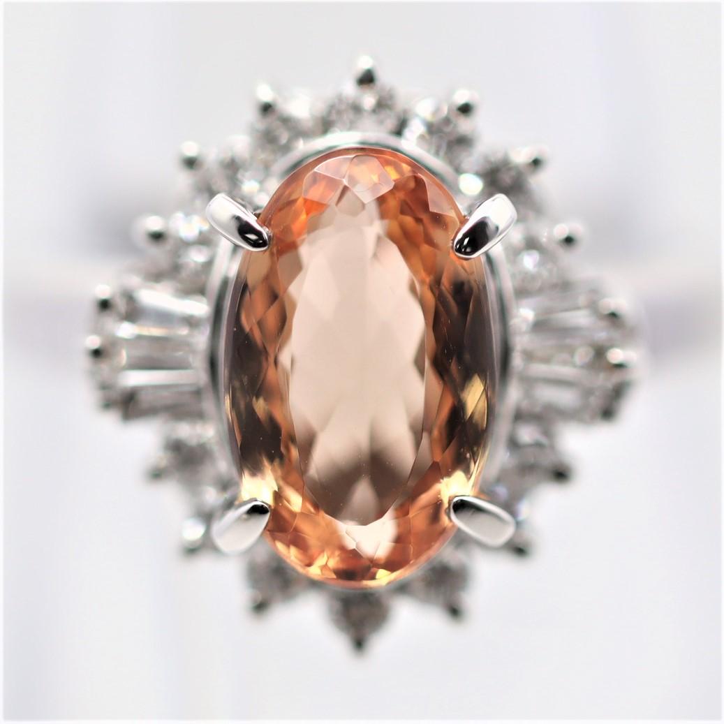 A simple yet fine platinum ring featuring a 4.02 carat oval-shape topaz with a fine vivid pinkish-orange color giving it the trade name “imperial.” It is complemented by 0.45 carats of diamonds set around it in a stylish pattern. Hand-fabricated in