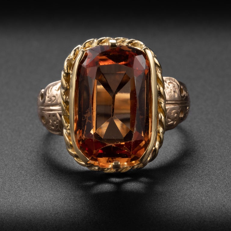 This is a genuinely impressive and rather spectacular ring. It features a large, cushion-cut reddish-orange imperial topaz that has been certified natural and untreated, The gem comes from Brazil. Imperial topaz is a rare gemstone and stones over 5