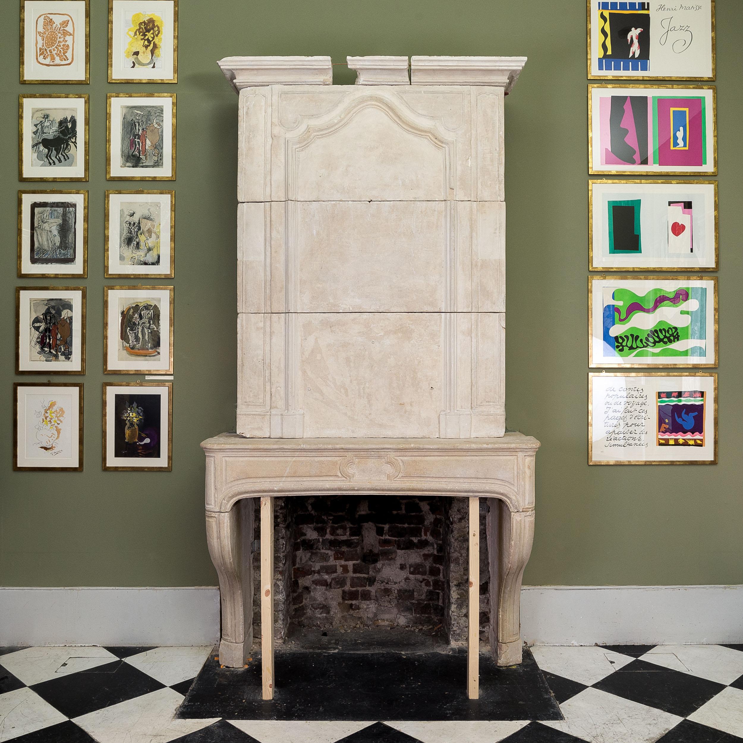 An impressive French Louis XVI limestone chimneypiece, eighteenth century, with stepped carved cornice, leading to the trumeau section centred by carved frame, flanked by long carved panels above the deep mantle decorated with further panelled