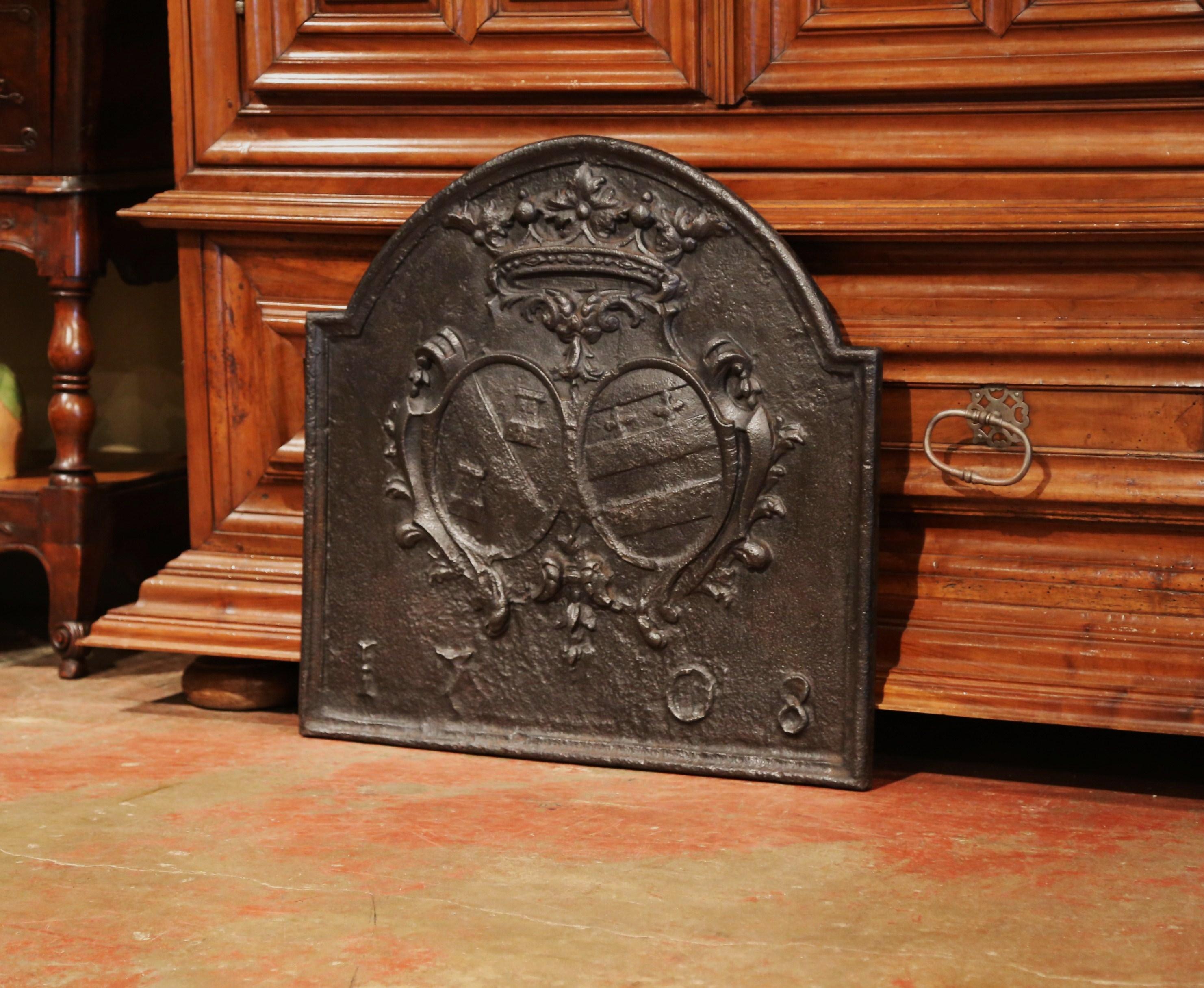 Decorate your fireplace or kitchen back splash with this large forged antique fire back. Created in Southern France and dated 1708, the Louis XIV period carved piece features an arched top with an intricate crown at the pediment, and a family coat