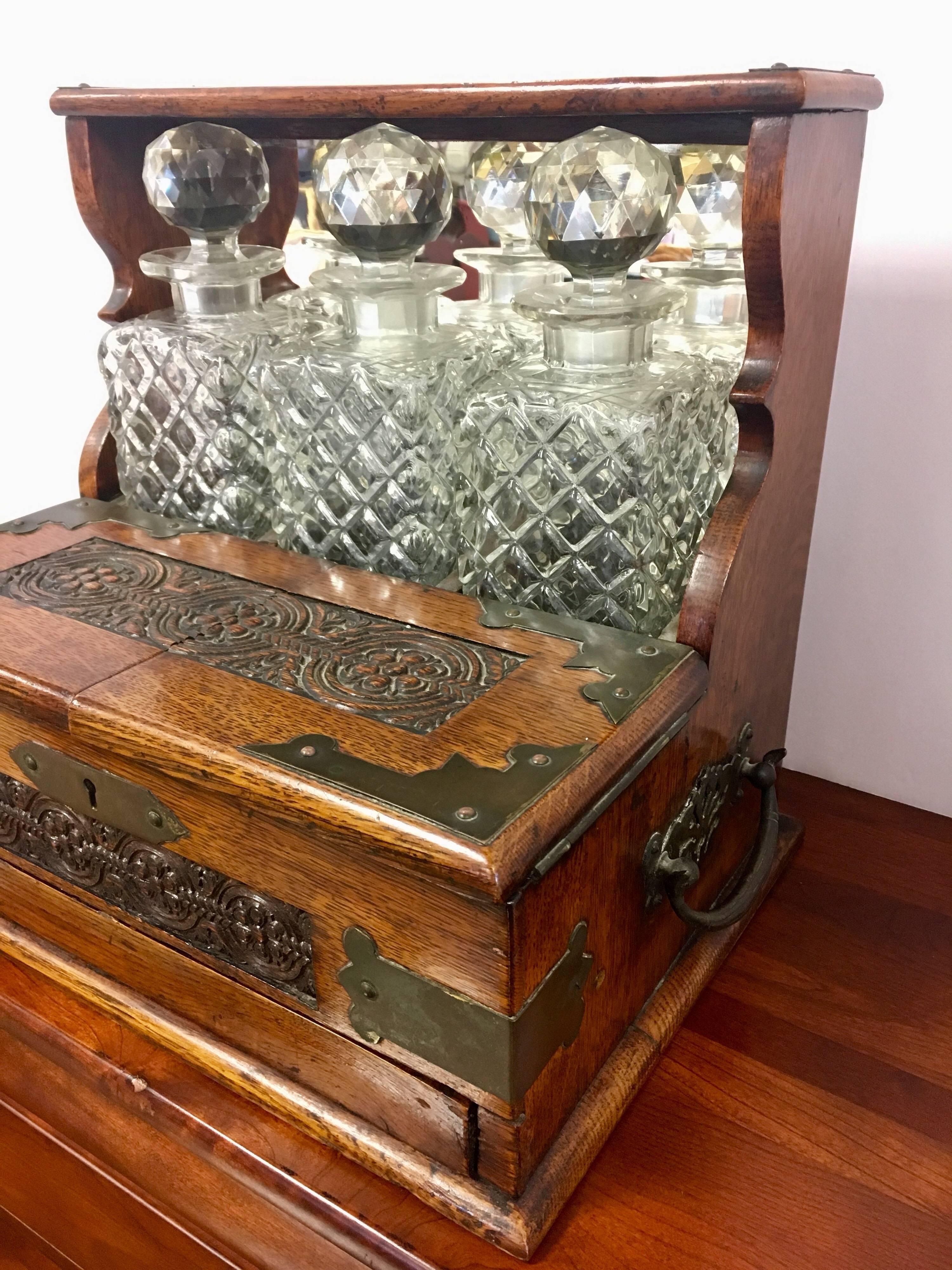 Ultra rare 19th century English oak and crystal tantalus decanter set with hidden lower drawer that pops open when wooden button is depressed to show a cribbage board.
 