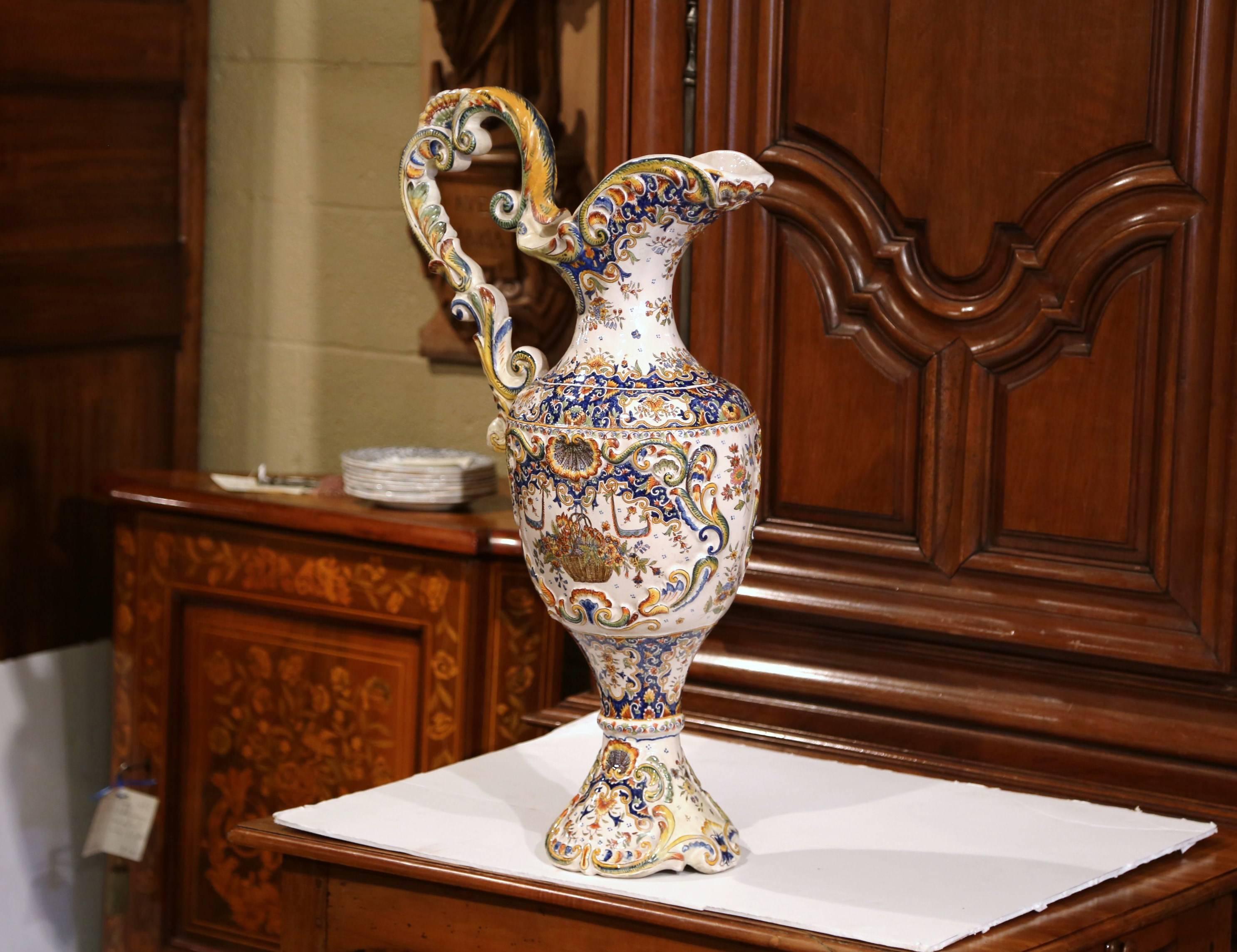 Diese hohe, antike Aiguiere wurde um 1860 in Rouen, Frankreich, hergestellt. Dieser zierliche, verzierte Keramikkrug hat einen großen Henkel, einen abgeschrägten Ausguss, vier Füße und eine insgesamt elegante Form. Die farbenfrohe Fayence-Vase zeigt