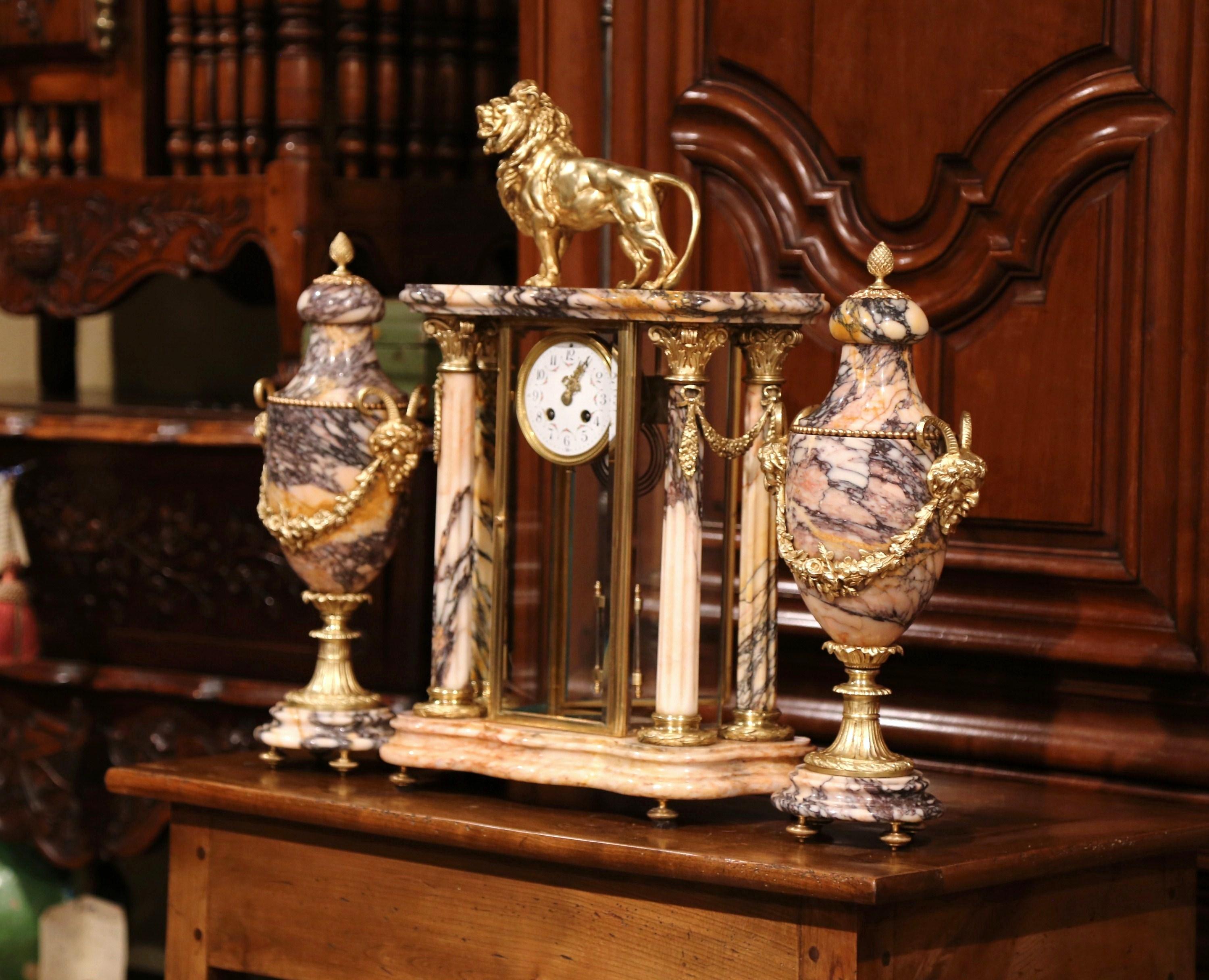 Decorate your mantel with this large antique Empire clock garniture set; crafted in Paris, circa 1860, the time keeper sits on a grey and beige marble bases with four round columns surmounted by a bronze lion sculpture standing proudly at the top.