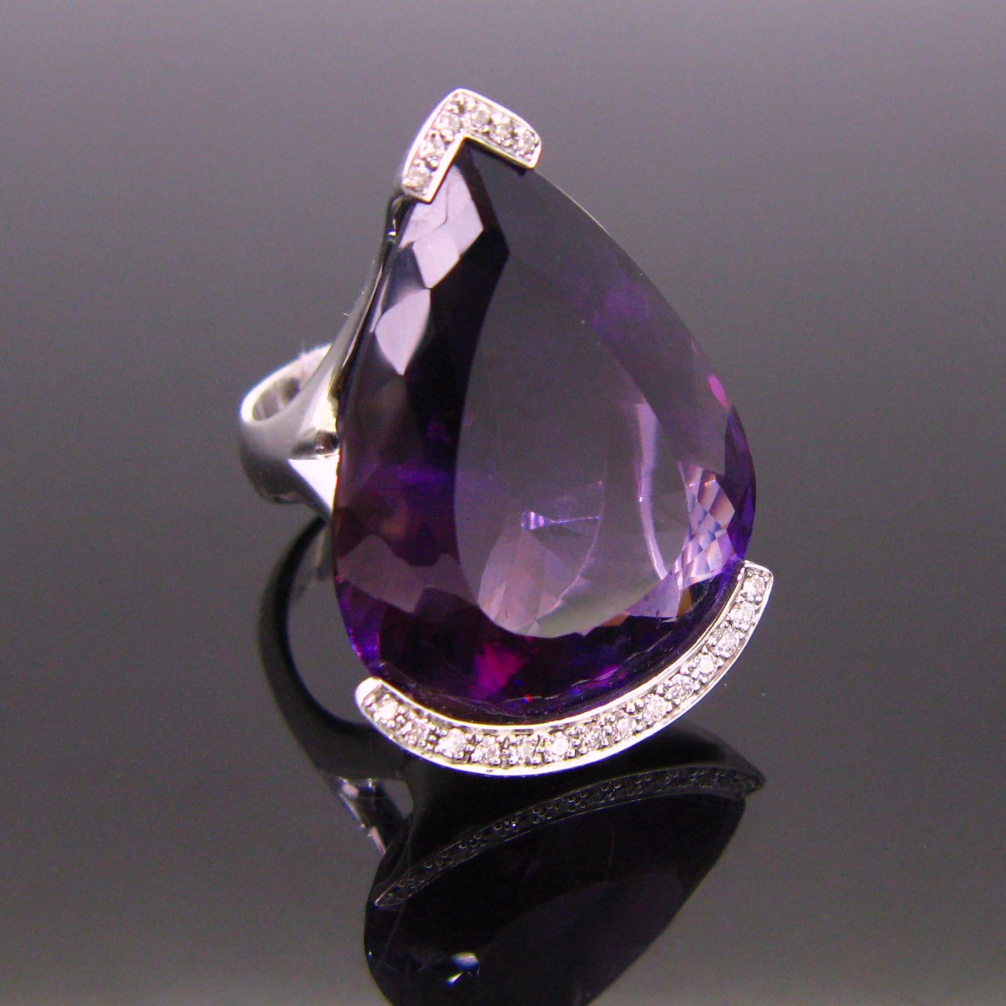 This important ring is adorned with a stunning amethyst, pear shape with a beautiful deep purple color. The 18kt white gold ring was designed by the French jeweler Philippe Comoy. The amethyst weighs approximately 60ct (measurements : 32.71mm x