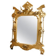 Important and big richly carved and gilded mirror with sculpture, Italy