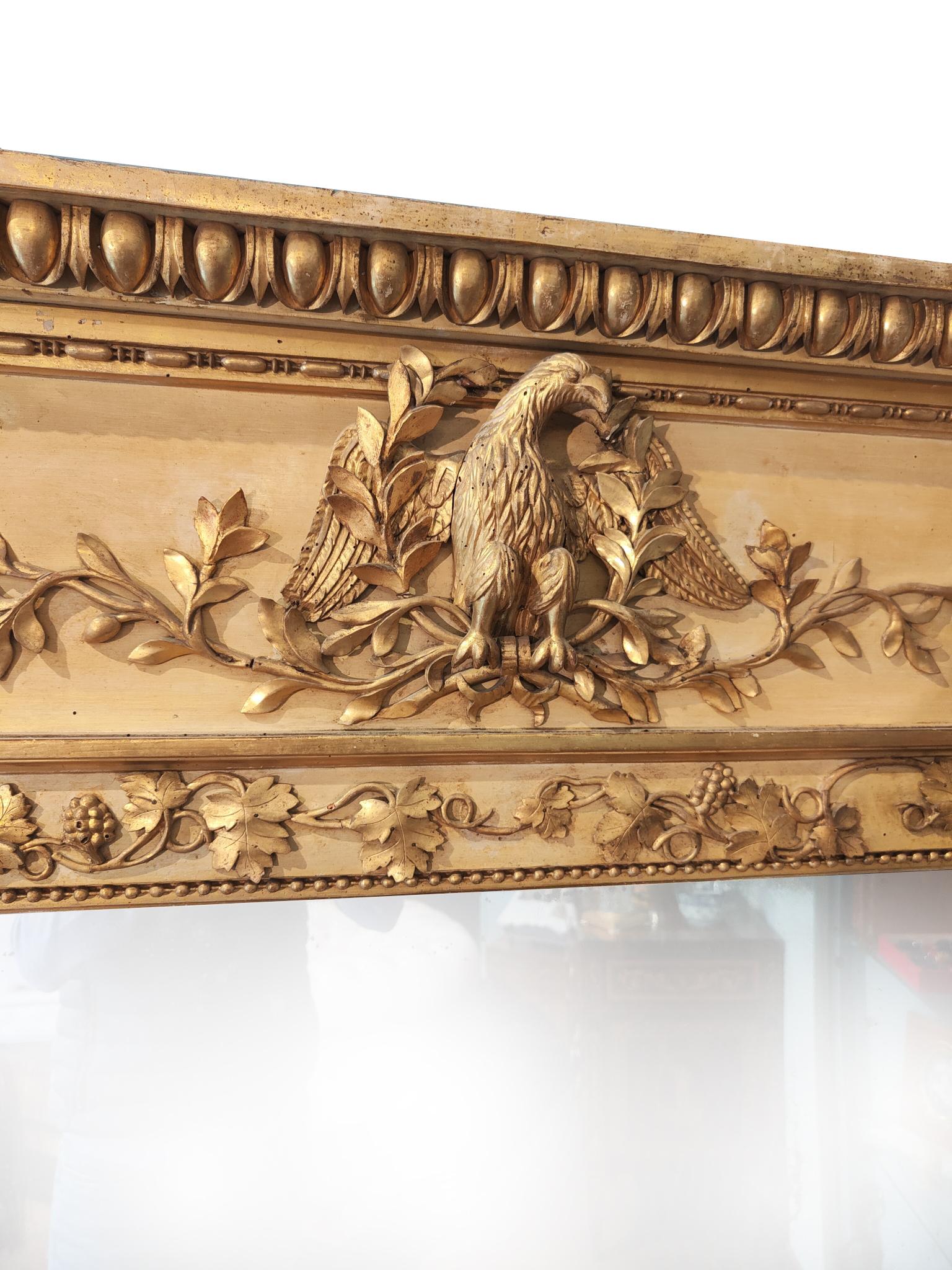 Important and large neoclassical mirror.
Large Italian mirror finely carved in all its parts. The upper part is characterized by a large figure of a bird while the entire part of the frame is characterized by vine leaves and bunches of