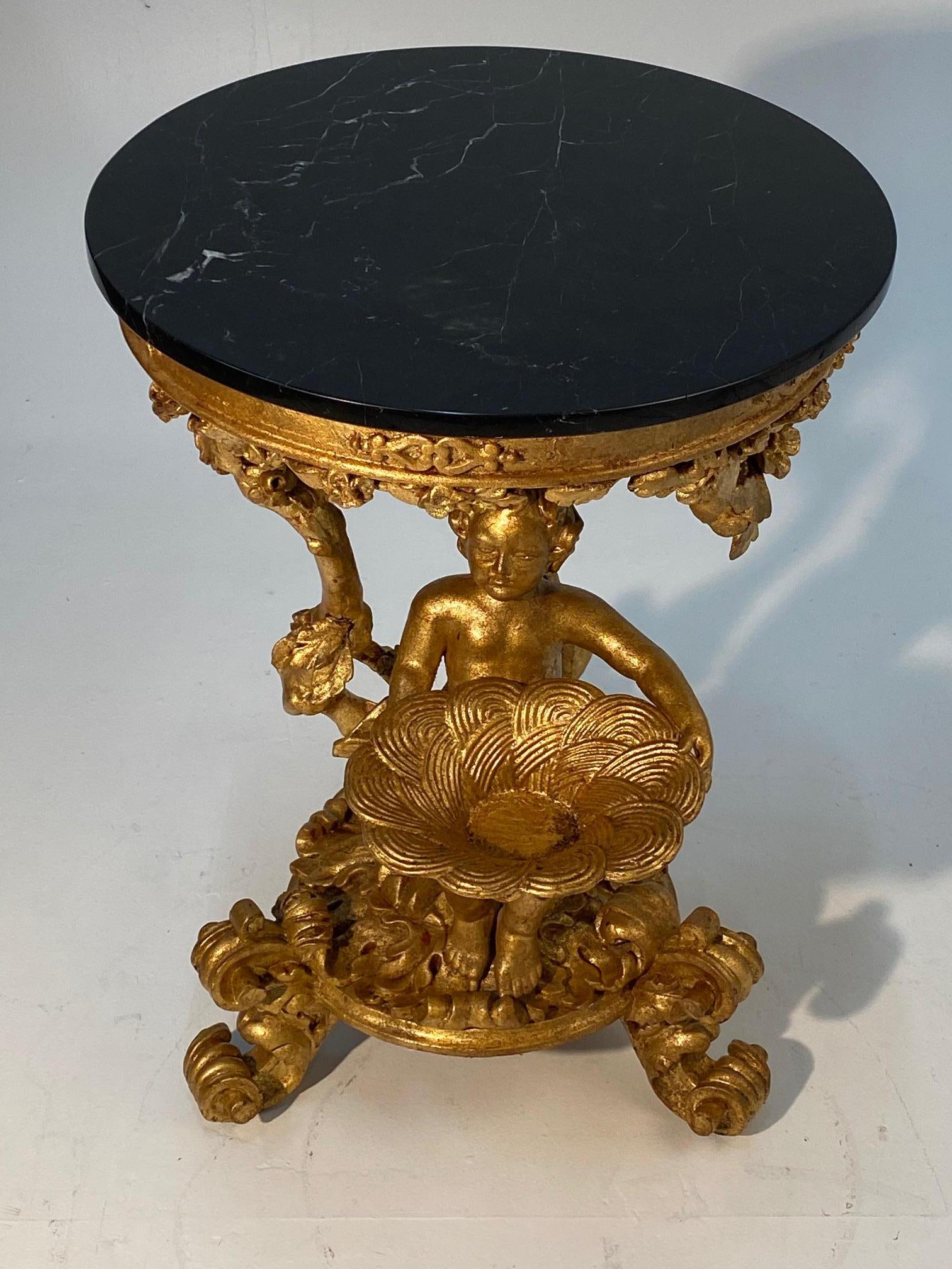 A show stopper ornate Rococo Italian center table having meticulously detailed gesso and gilded carved wood base with putti and black marble top.