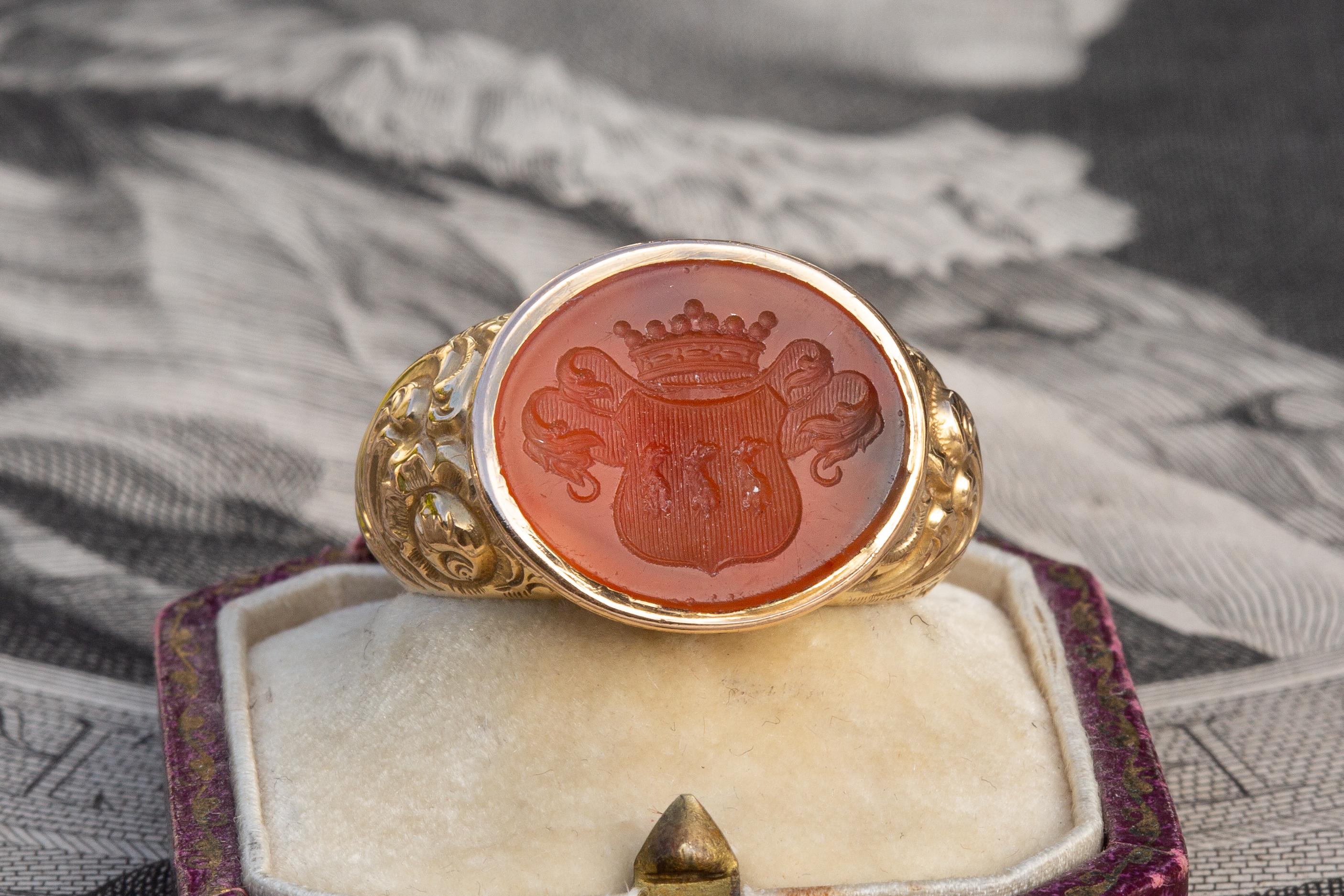 Superbe et rare bague finlandaise ancienne en or 18 carats, fabriquée à Helsinki en 1854. L'intaille ovale des armoiries en cornaline est sertie dans une grande monture en or repoussé aux motifs feuillagés et complexes. Grâce à un jeu complet de