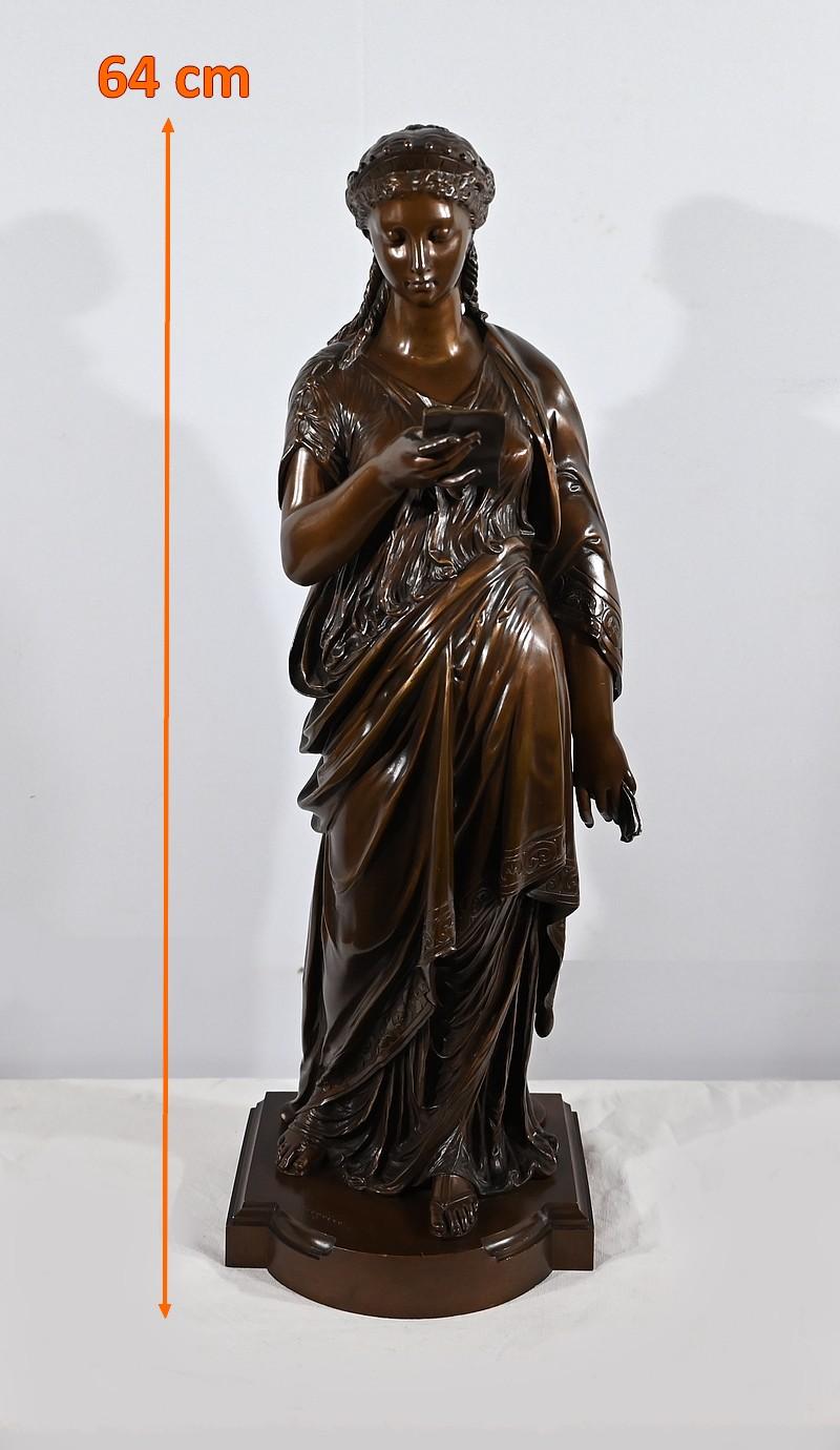 Grand bronze à patine brune de Jean-Louis Grégoire (1840-1890) représentant une jeune femme à l'antique lisant une lettre. De la main droite, la jeune femme, coiffée d'une couronne qui retient ses cheveux bouclés, lit consciencieusement sa missive,