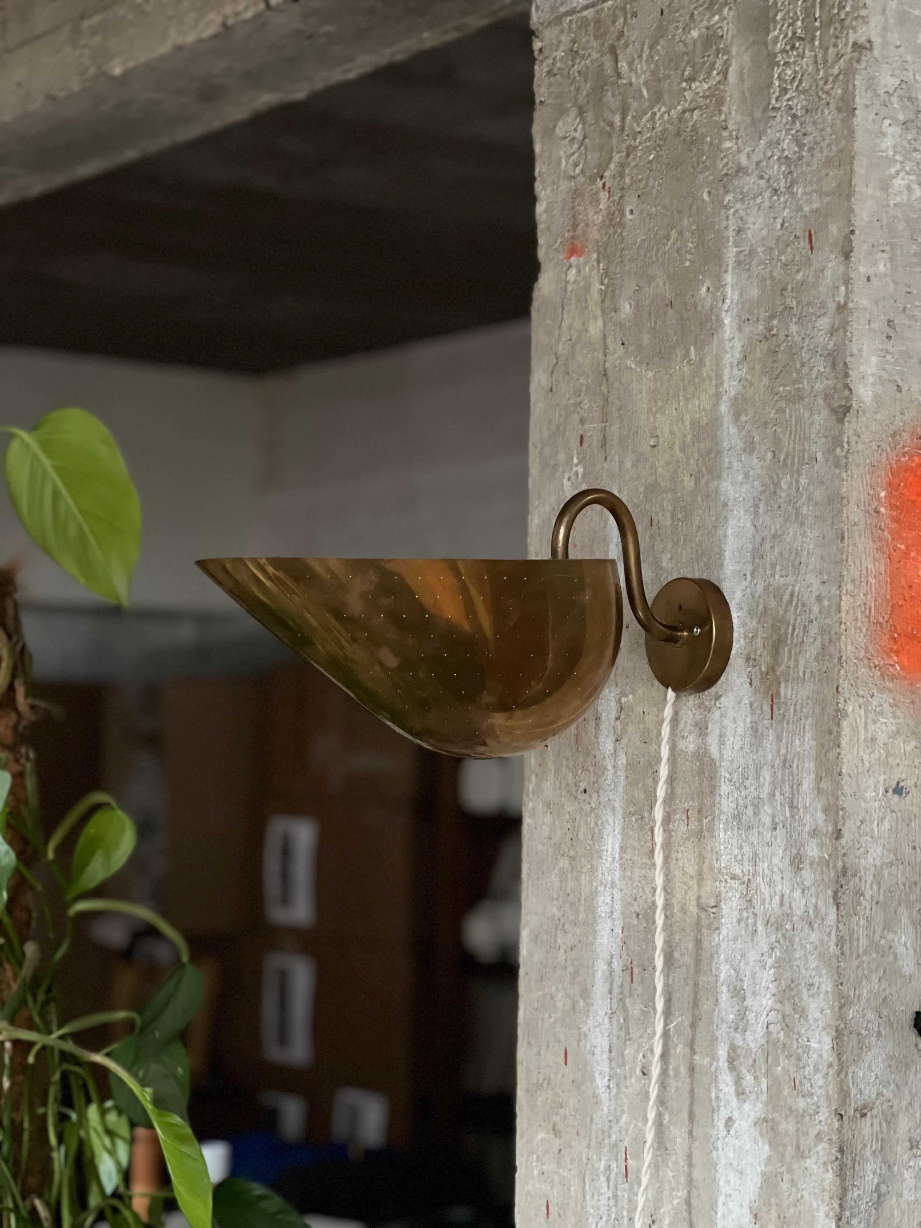 One of most influant Swedish architects of the early 1900. Brass wall lamp that can be used down or up. Large reflector with tiny holes with a curved arm. Elegant, minimal and classical at the same time. A true master