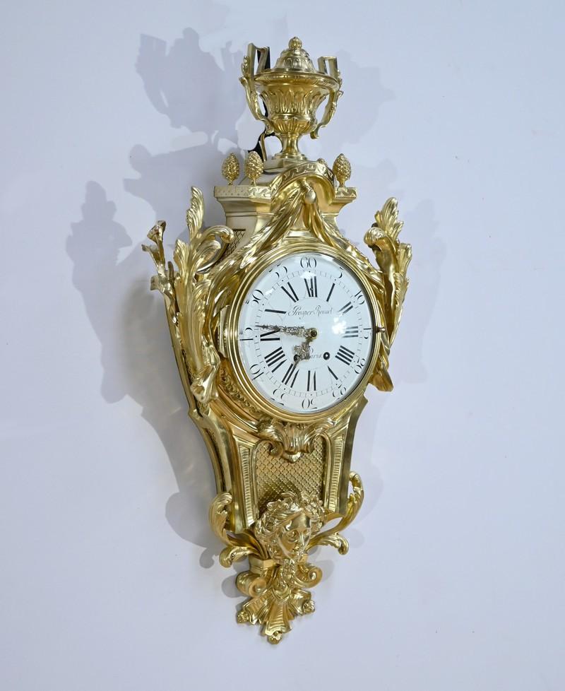 Reloj de pared de bronce dorado finamente cincelado del relojero parisino Prosper Roussel.
Está rematado con un jarrón cerrado y cuatro piñas.
También está adornado con tallas de hojas de acanto y un rico drapeado.
La esfera esmaltada en blanco