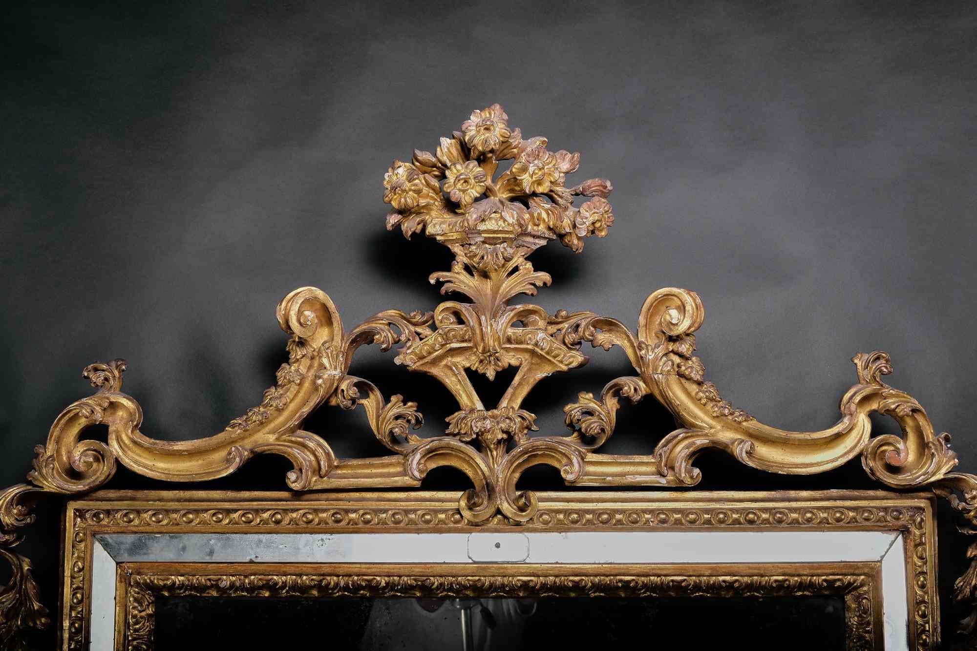 The streamlined frame adorned with an acanthus frieze is covered with mirrors and decorated with decorative engravings all around. The beautifully openwork pediment is surmounted by a cup of flowers. The sides are decorated with garlands of flowers,