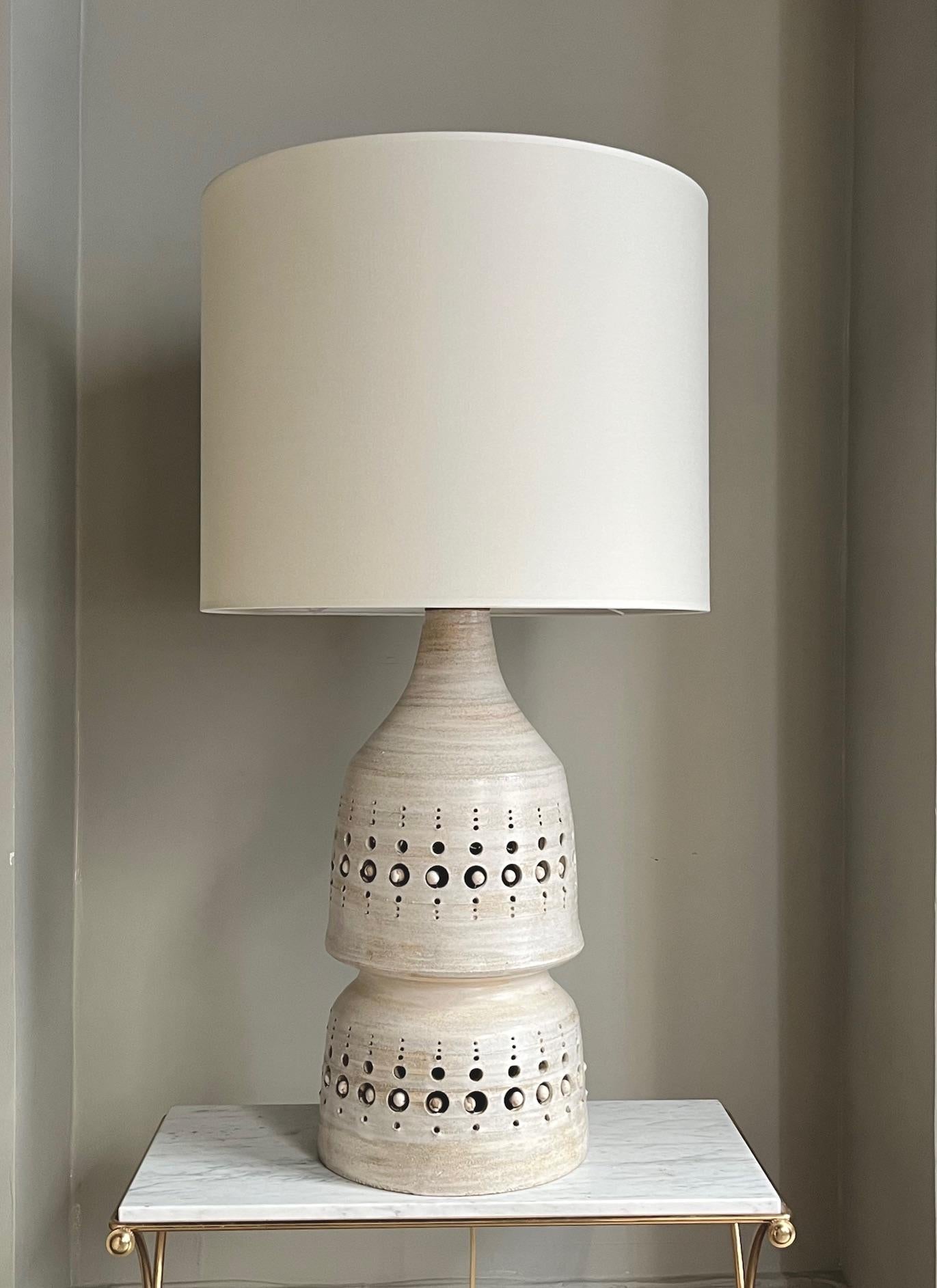 Tall glazed ceramic table lamp. 
Openwork around the whole body of the lamp.
The ceramic is glazed in shades of cream or beige. 
Double electrification with light inside the lamp's body 
Rewired 
Circa 1970.
Georges Pelletier ( 1938/2024)

Height