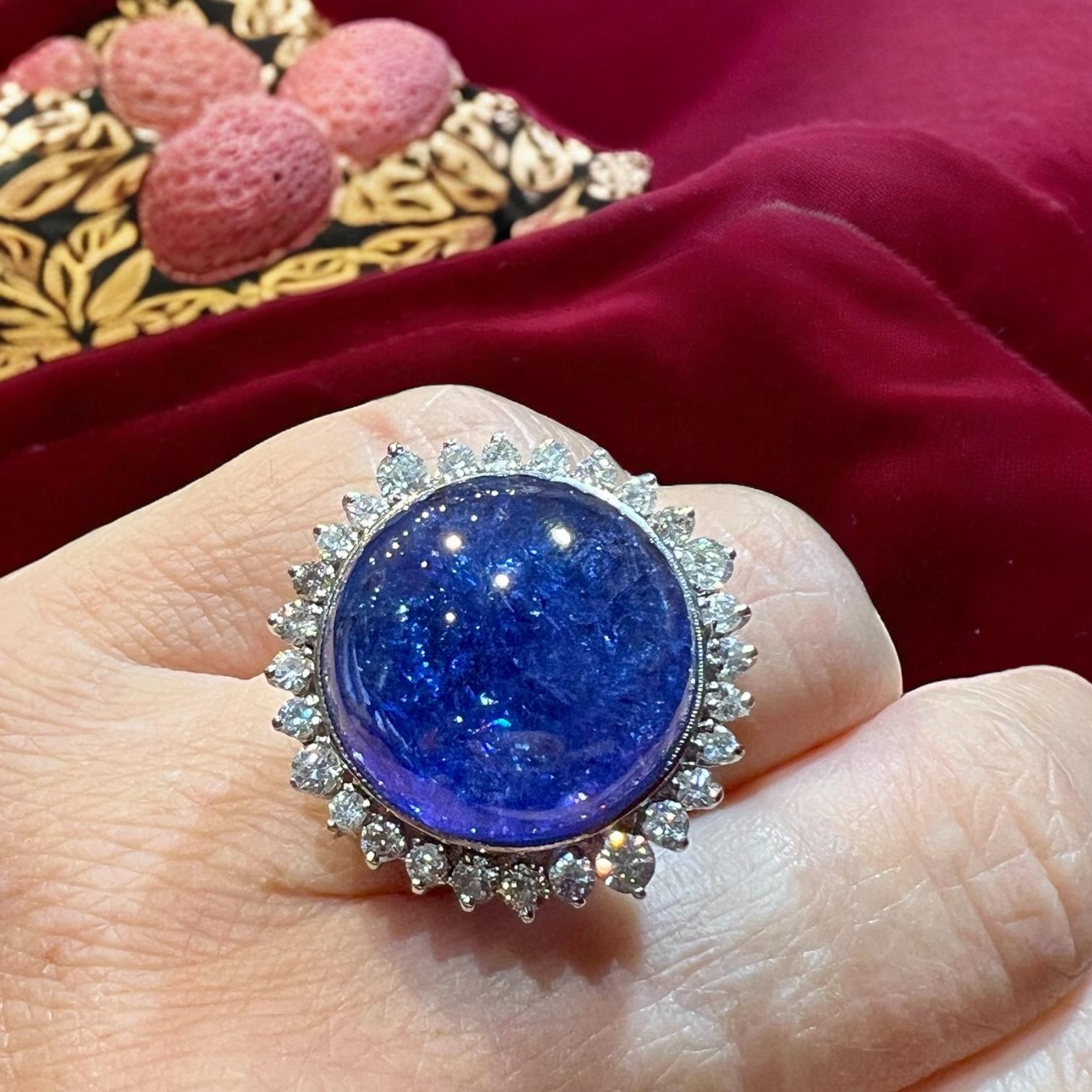 Eine seltene und beeindruckende Kreation mit einem spektakulären 33 Karat Tansanit-Cabochon (Ø ca. 3 cm, Höhe 1,5 cm).
Seine faszinierenden pleochroitischen Farbtöne - von tiefem, samtigem Blau bis hin zu leuchtendem Violett - offenbaren lebendige