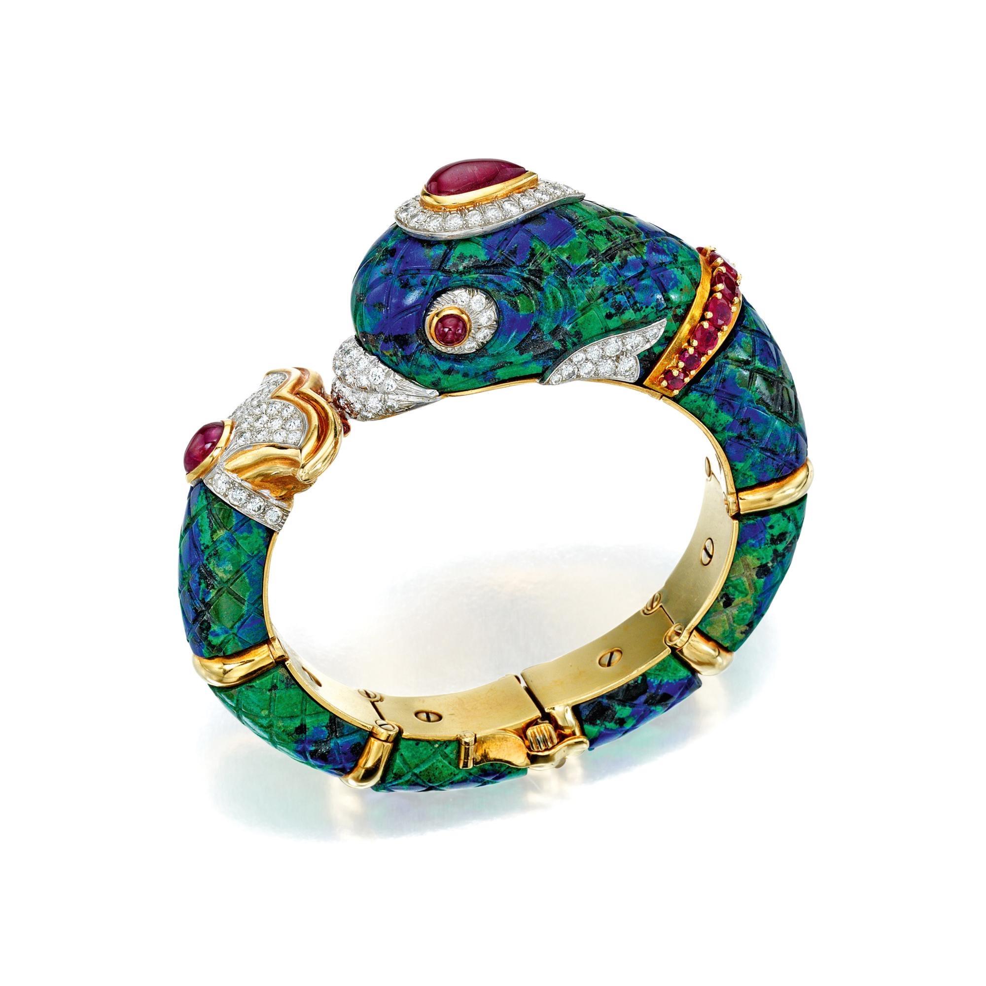 An important David Webb dolphin bracelet composed of carved azurmalachite segments, accented with round diamonds, further decorated with cabochon and round rubies. Internal circumference 6 inches, width 3/4 inches, gross weight approximately 84