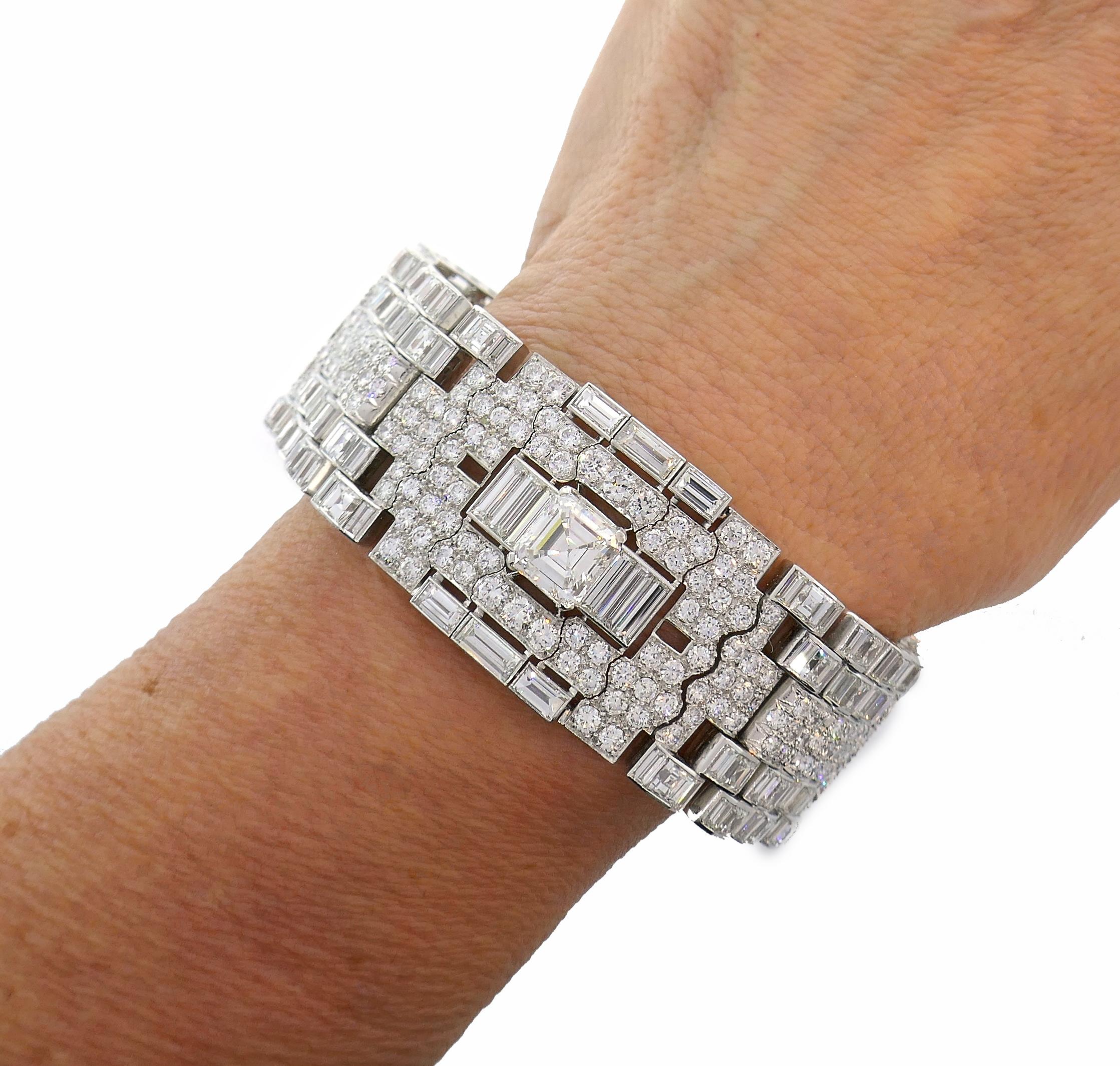 Atemberaubendes Art-Deco-Revival-Armband aus den 1960er Jahren. Er ist aus Platin gefertigt, mit drei Diamanten im Smaragdschliff besetzt und mit runden Brillanten und Diamanten im Stufenschliff verziert. Die drei größeren Diamanten im