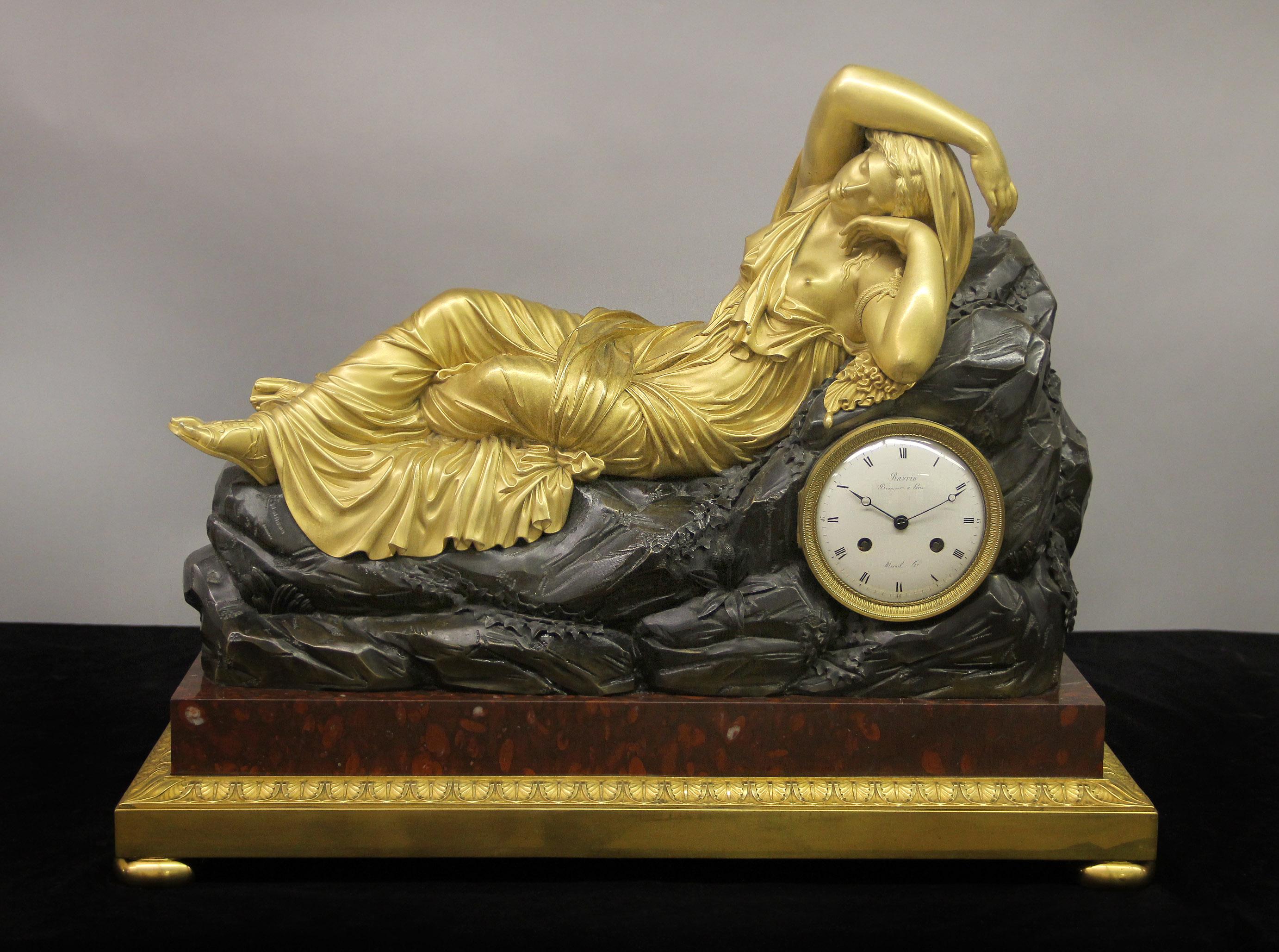 An Important Early 19th Century Gilt and Patinated Bronze Figural Mantle Clock

By Andre-Antoine Ravrio and Mesnil

Modeled with a large and beautiful gilt bronze figure of recumbent Cleopatra, on a rouge griotte marble and gilt bronze base with bun