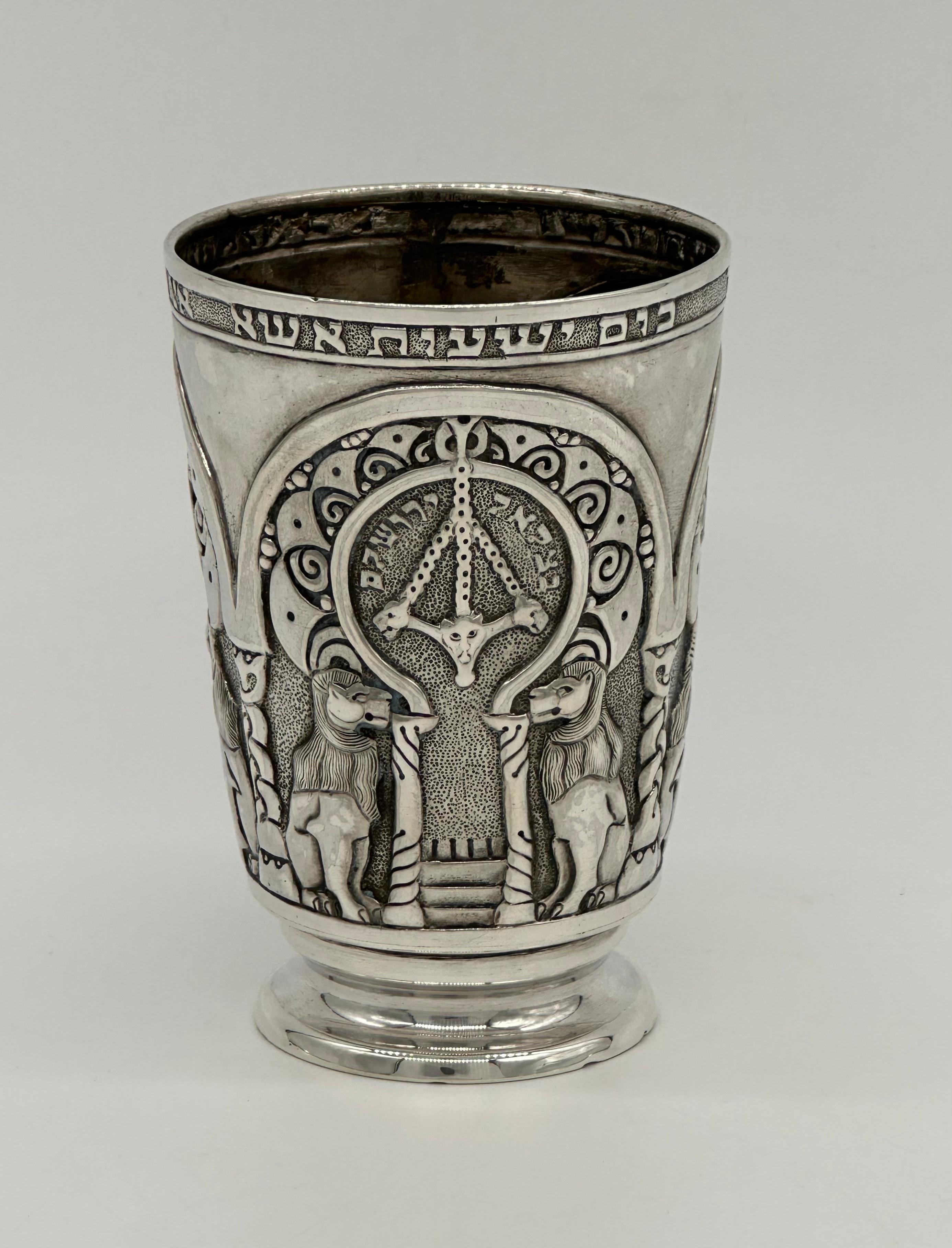 Important Handmade sterling silver Kiddush goblet by Bezalel School, Jerusalem, Circa 1910-1913. 
On the cup there are 3 identical scenes of flanked lions and on the middle of them There are two columns with a staircase, this design is probably
