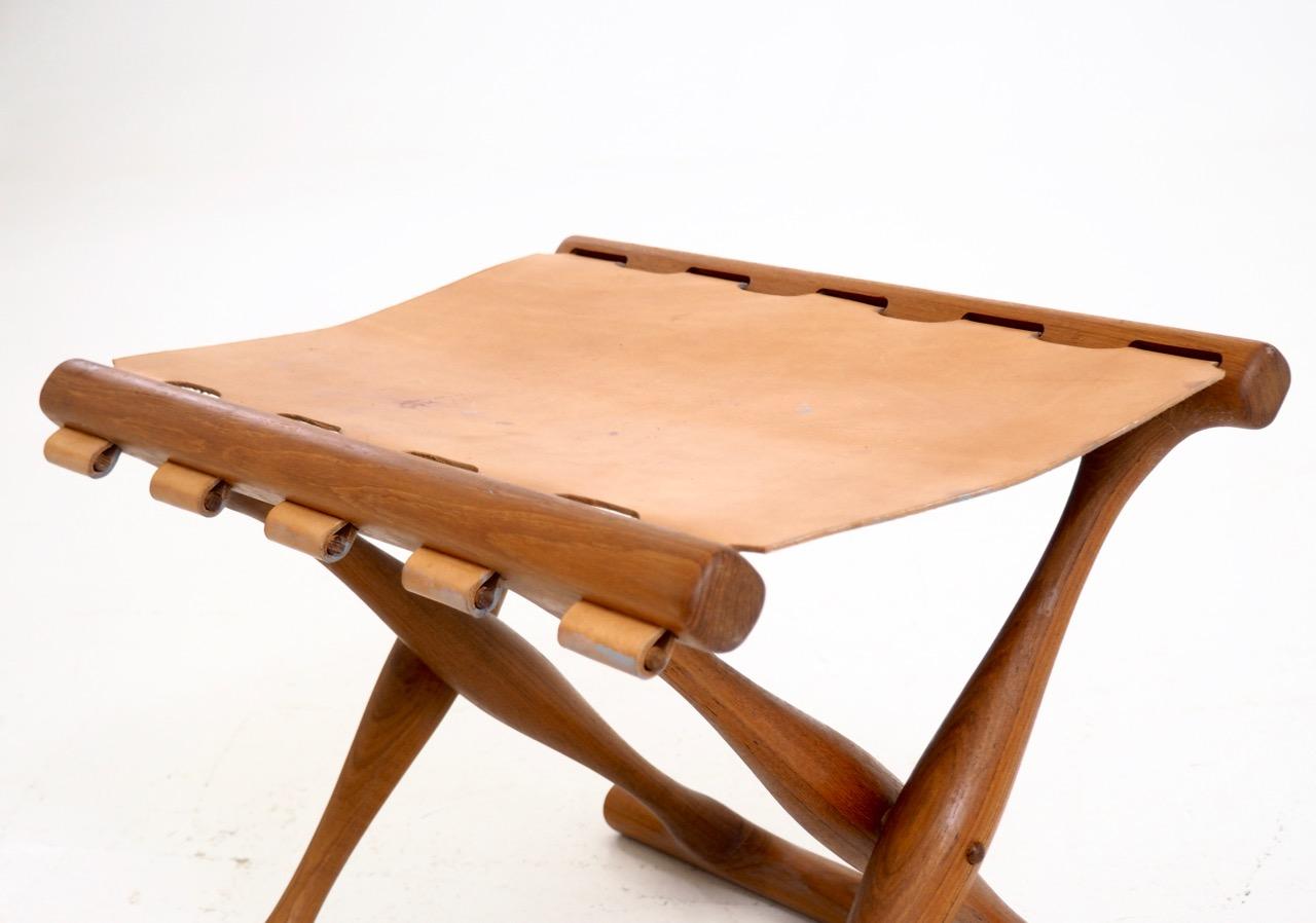 Important folding stool by Poul Hundevad in teak wood and leather seat
Measures: H. 39 W. 48 D. 36 cm 
H. 15.3 W. 18.8 D. 14.1 in.