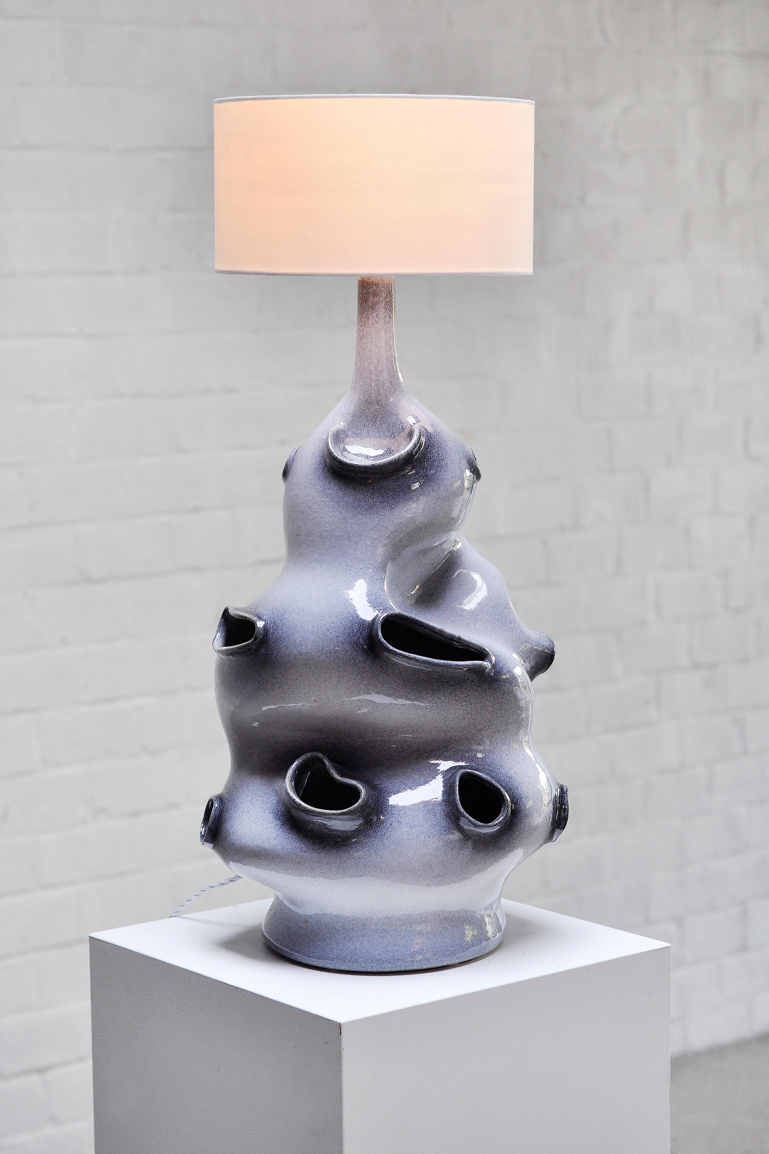 A monumental French table lamp with a sculptural ceramic base, made in France in the early 70s. This large blue tone glazed ceramic lamp features organic and abstract Formations giving it a sculptural and very unique appearance. With its height of