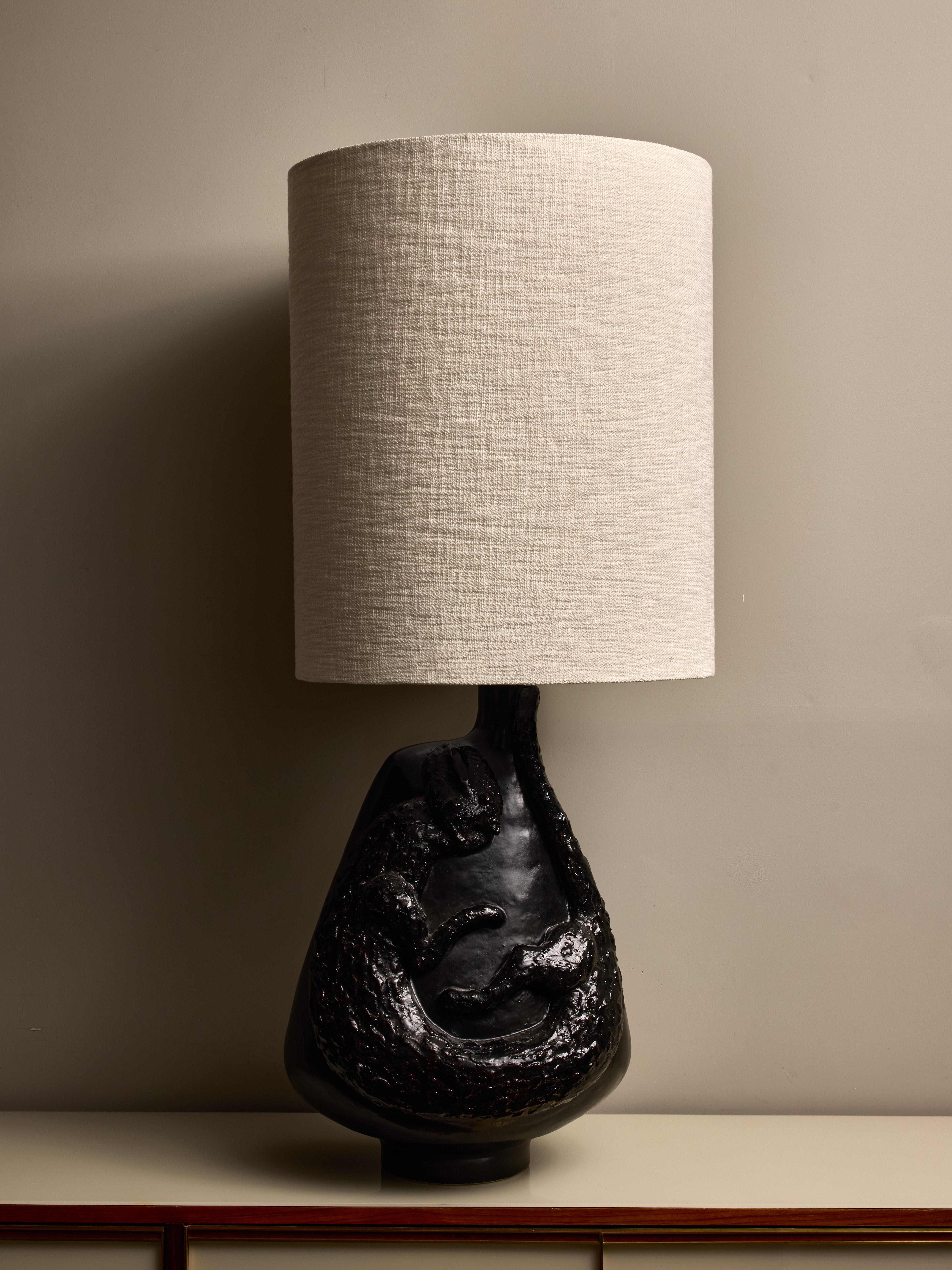 Une grande lampe de table en céramique fabriquée par le célèbre duo de céramistes français, Les Dalo. La face avant présente un animal stylisé qui ressemble à un chat et qui se contorsionne pour s'adapter. 
Signature des artistes au dos.
Dimensions