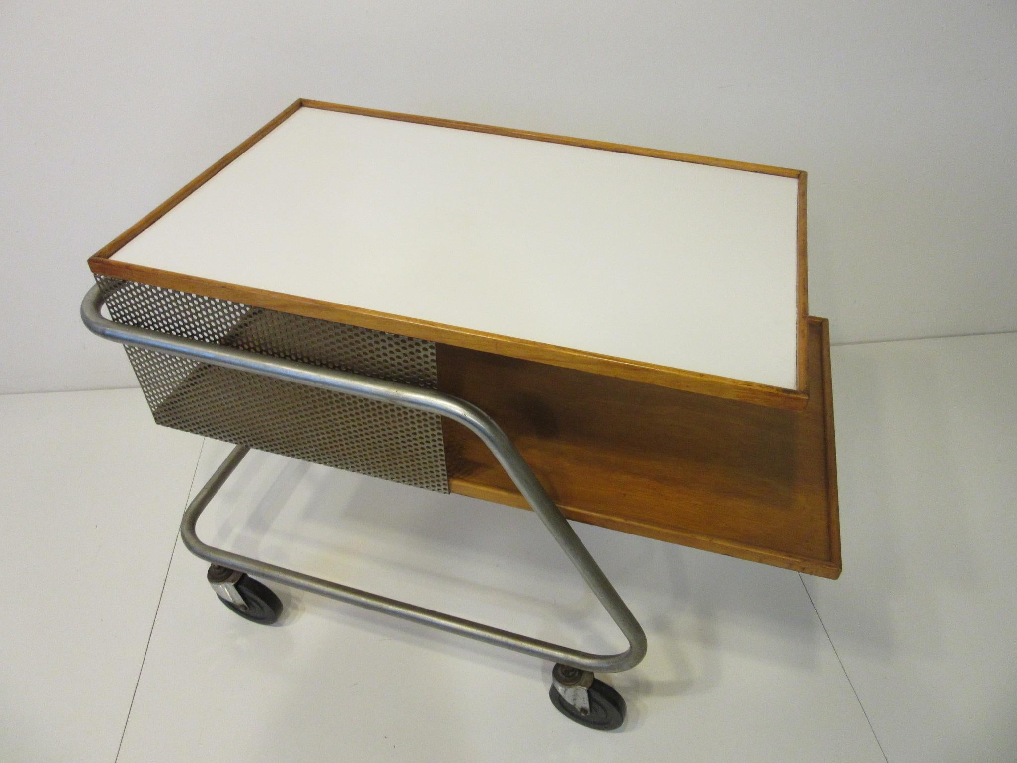 A perforated metal and wood bar / service cart with laminate top and rubber wheels rolling around on a steel tube frame. Franziska the designer studied Bauhaus design at Harvard under Gropius, Kepes, Moholy- Nagy and Breuer. This piece garnered wide