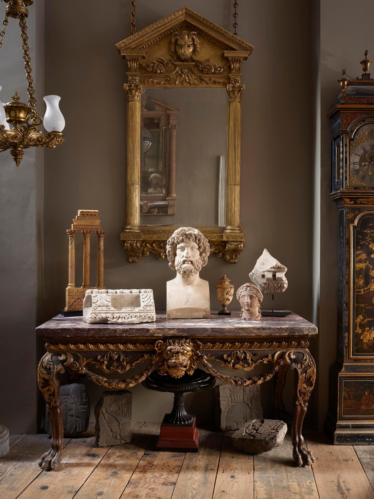 The architectural frame flanked by Corinthian columns with shaped base carved with swags framed by brackets, the cresting with triangular pediment centered by a lion mask issuing swags of flowers, fruit and wheat sheaves.
Note: The mirror plate is