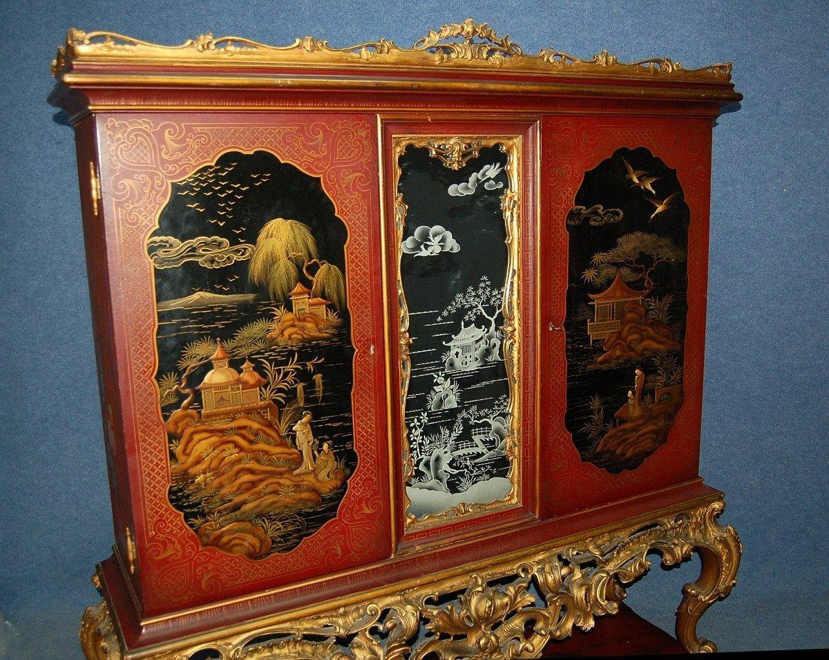 Japanese-style cabinet with lacquered decoration. It opens with two doors, in the center a mirror engraved with Far Eastern landscapes. Gold-coloured interior with floral decoration adorned with a mosaic of mirrors, two drawers. the piece of