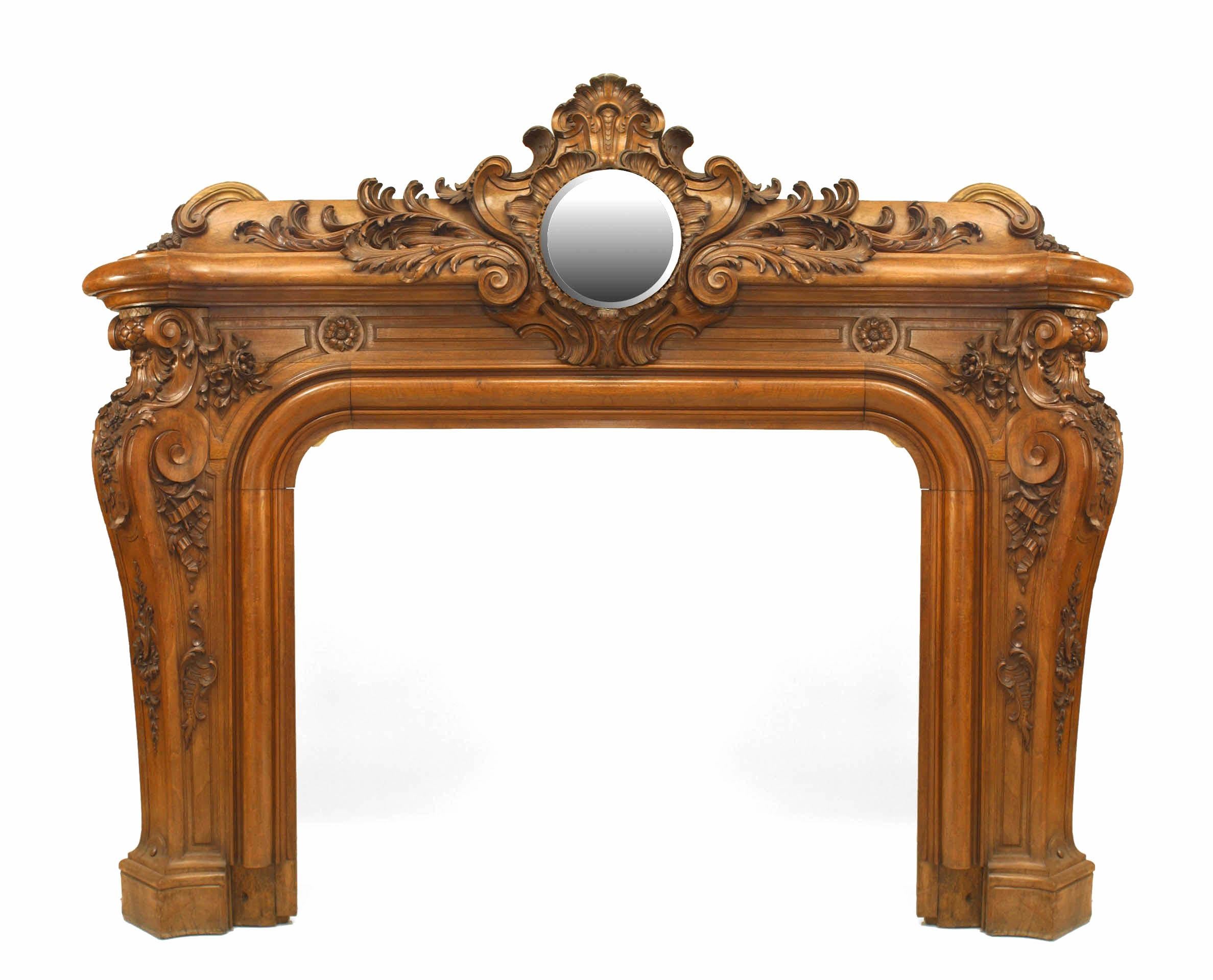 French Louis XV-style (3rd Quarter 19th Century) walnut fireplace mantel with a circular mirrored panel above a C scroll and rockwork carved surround (Reputedly from Napoleon III's library) (Related items: 031616, 032213).
