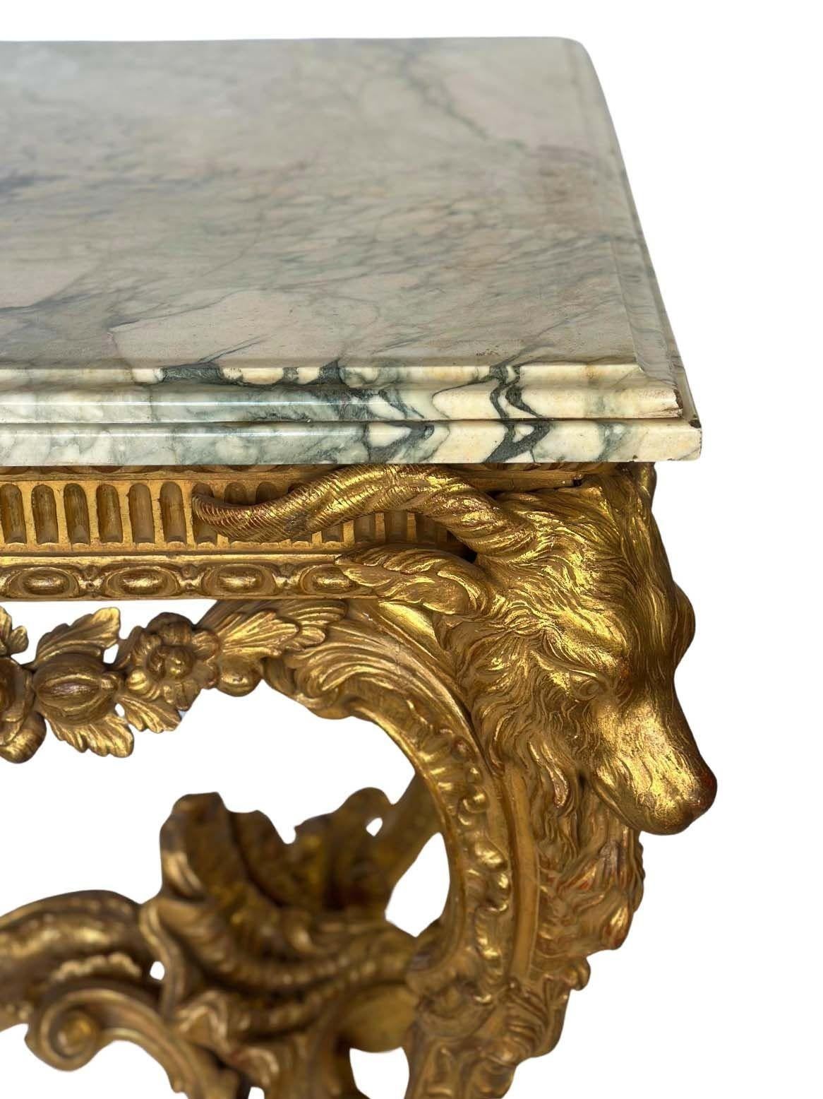 An impressive and richly carved English Neoclassical giltwood console table, the rectangular marble top resting above a deeply carved frieze centered by a satyr mask surrounded by floral swags and guilloche molding. The table is raised on four