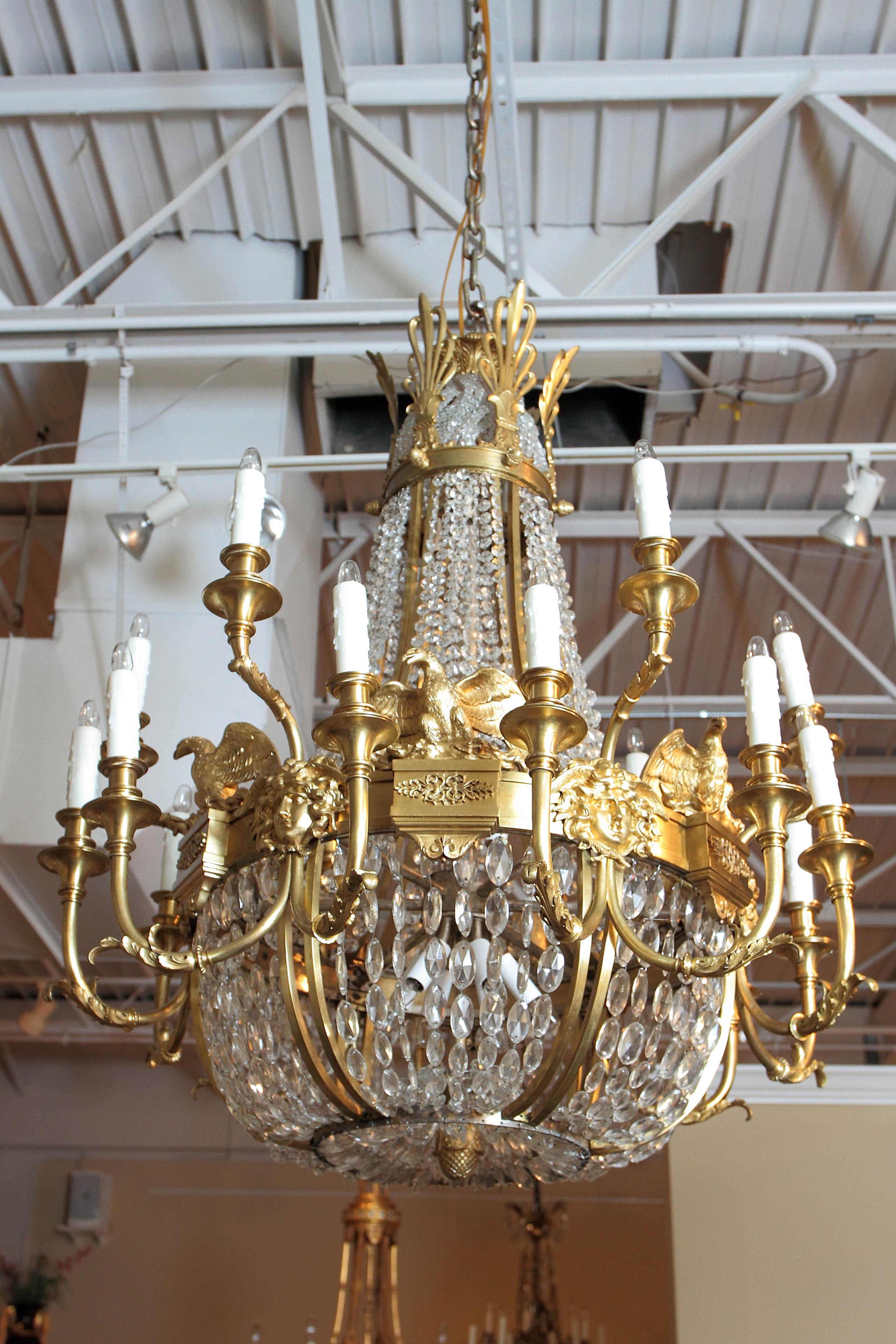 Late 19th century to Early 20th century American Empire cut crystal and gilt bronze chandelier. Fine gilt bronze Eagles atop a beautiful band of gilt bronze decoration with female faces. Adorned with 29 lights on the inside and the outside