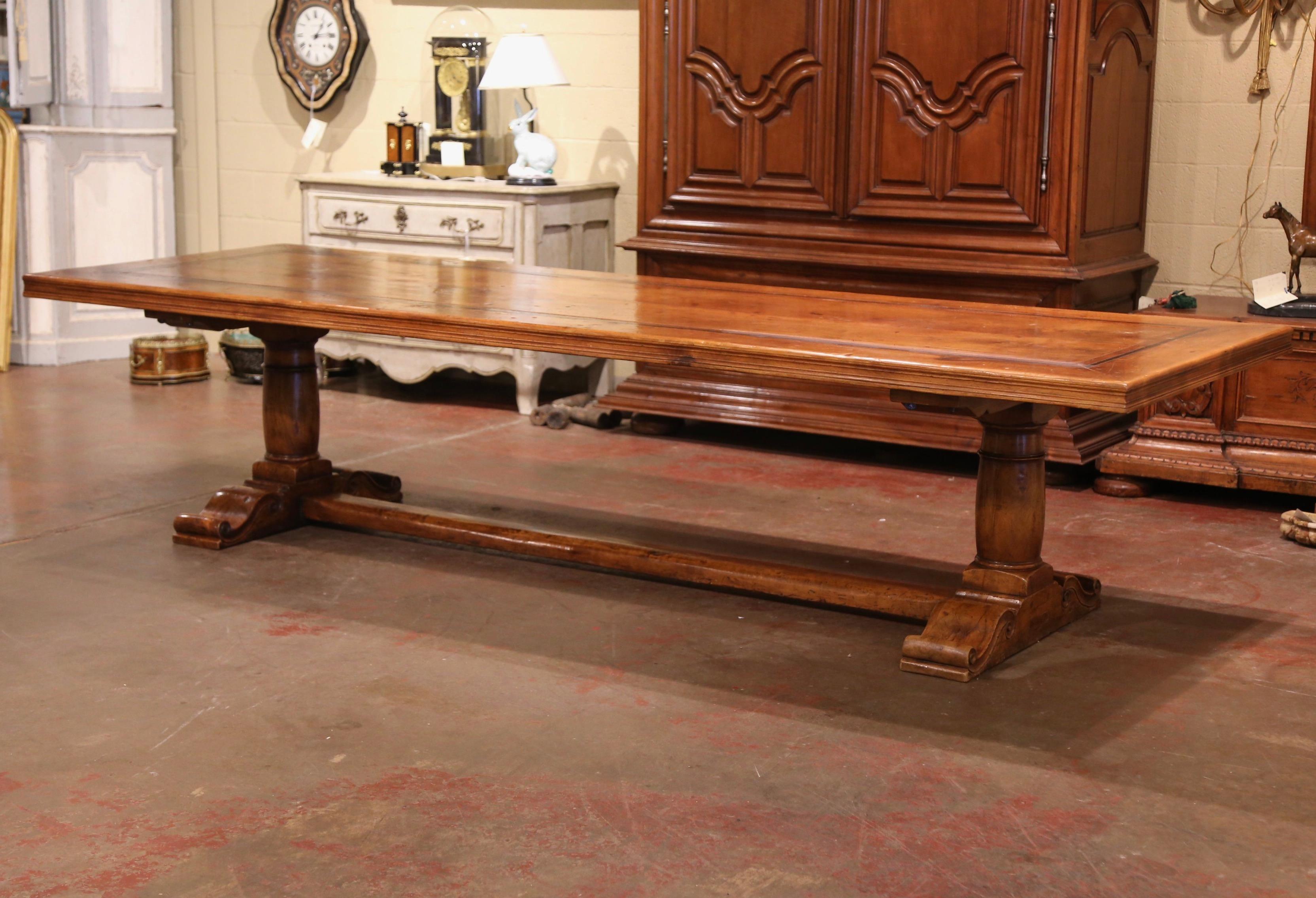 Almost 11 feet long, this large fruitwood dining room table was crafted in southwest France, near the Spanish and French border. Built with 18th century antique walnut timber, the table stands on a trestle base, with two hand carved baluster legs