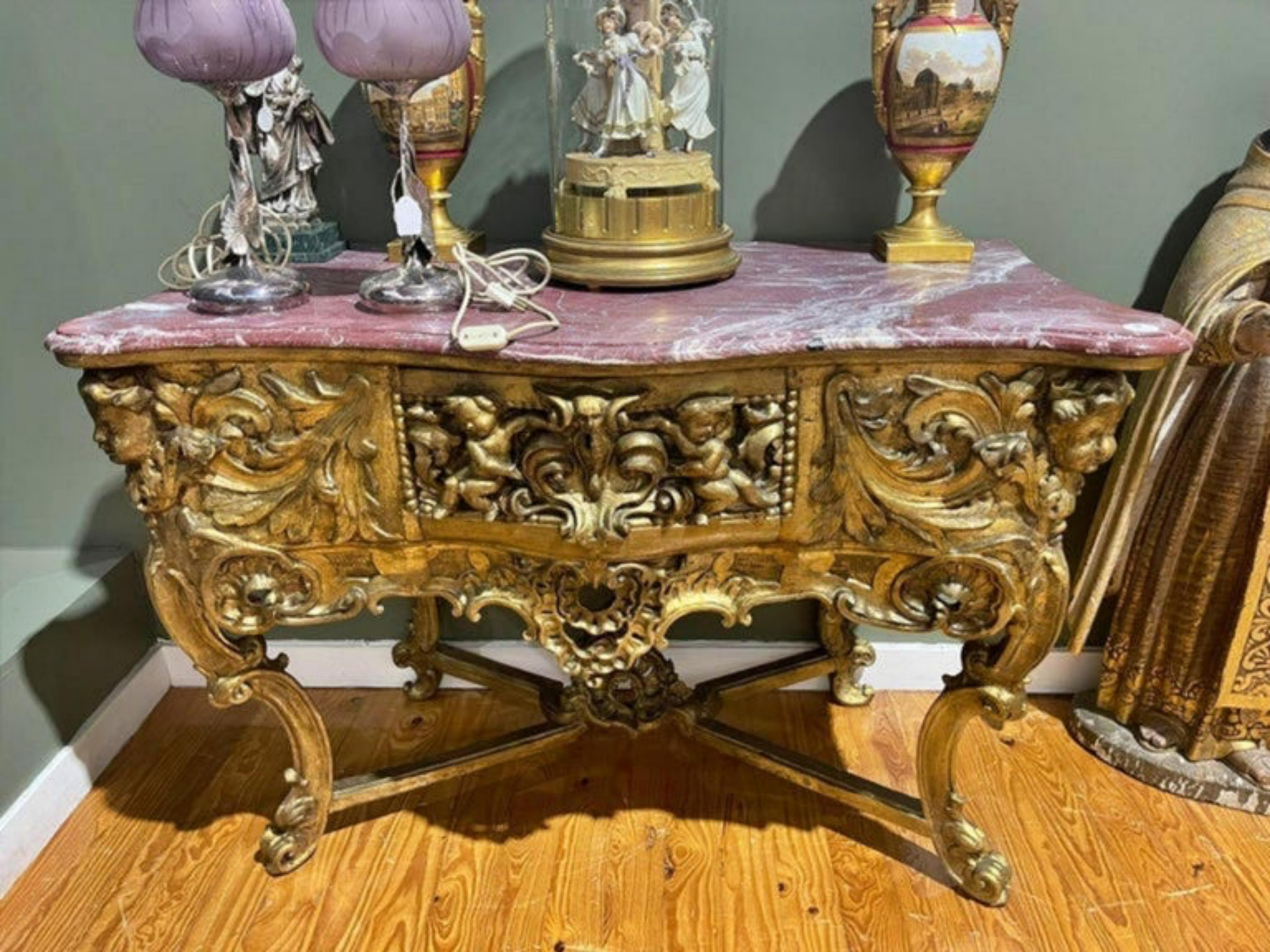 Great mobile (Credential)
Portuguese 18th century
in carved, pierced and gilded wood with a drawer. Decorated with angels, puttis and plant motifs, it rests on four curved legs ending in a winding, connected by an X beam. Top in pink marble. Flaws