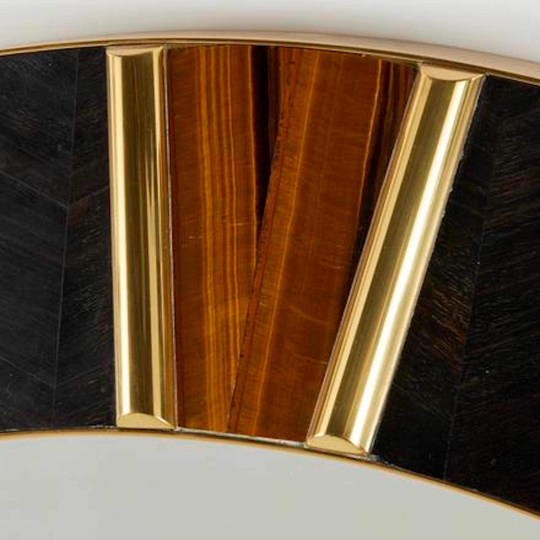 Important modernist marquetry and gilt brass circular mirror inlaid with tiger eye stone details.
 