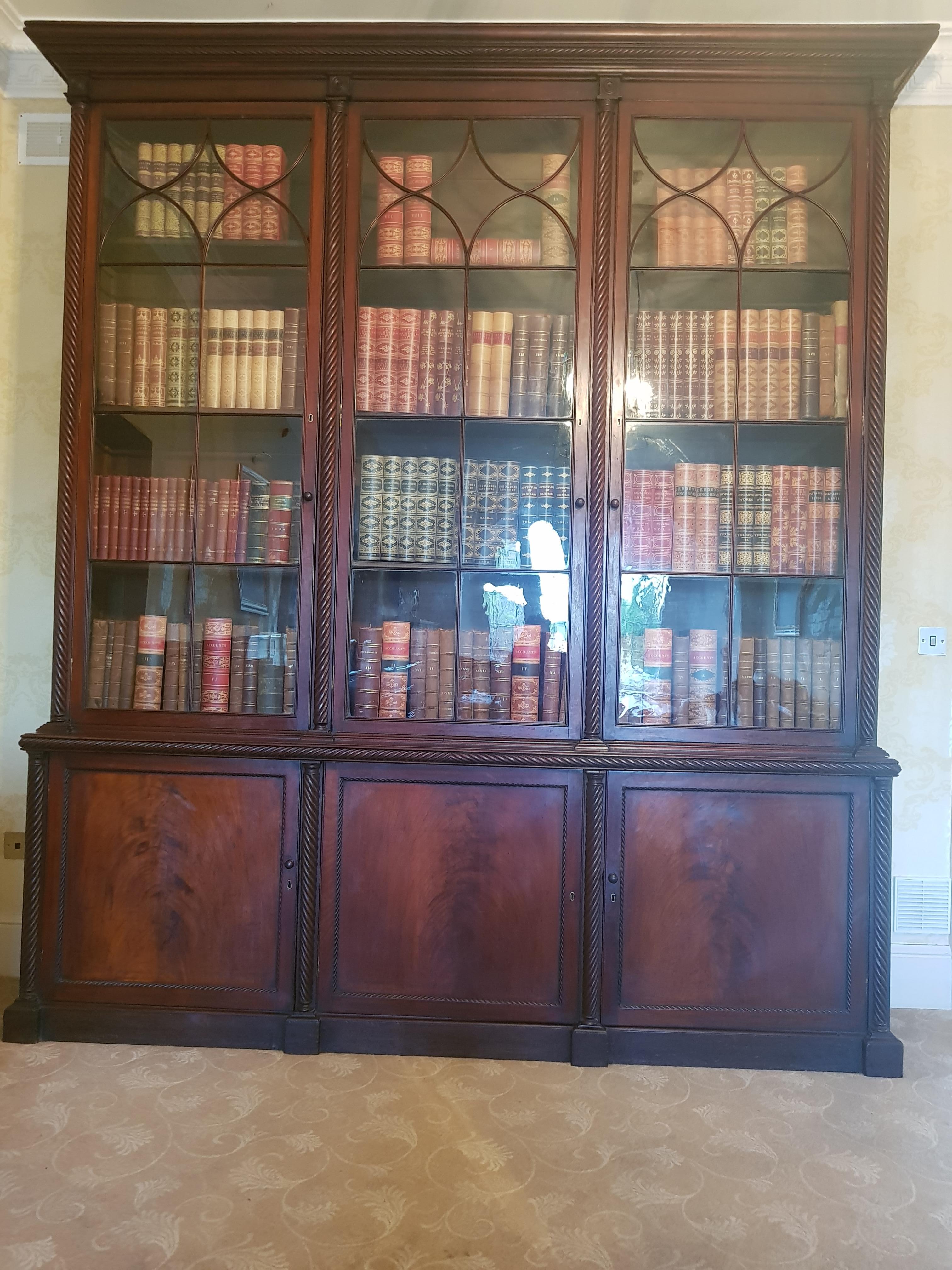 A very fine Irish Georgian mahogany bookcase, attributed to Mack, Williams & Gibton, with three opening glazed doors and shelving intersposed by Irish regency style rope twisted design pilasters terminating in circular mouldings to an upper cornice