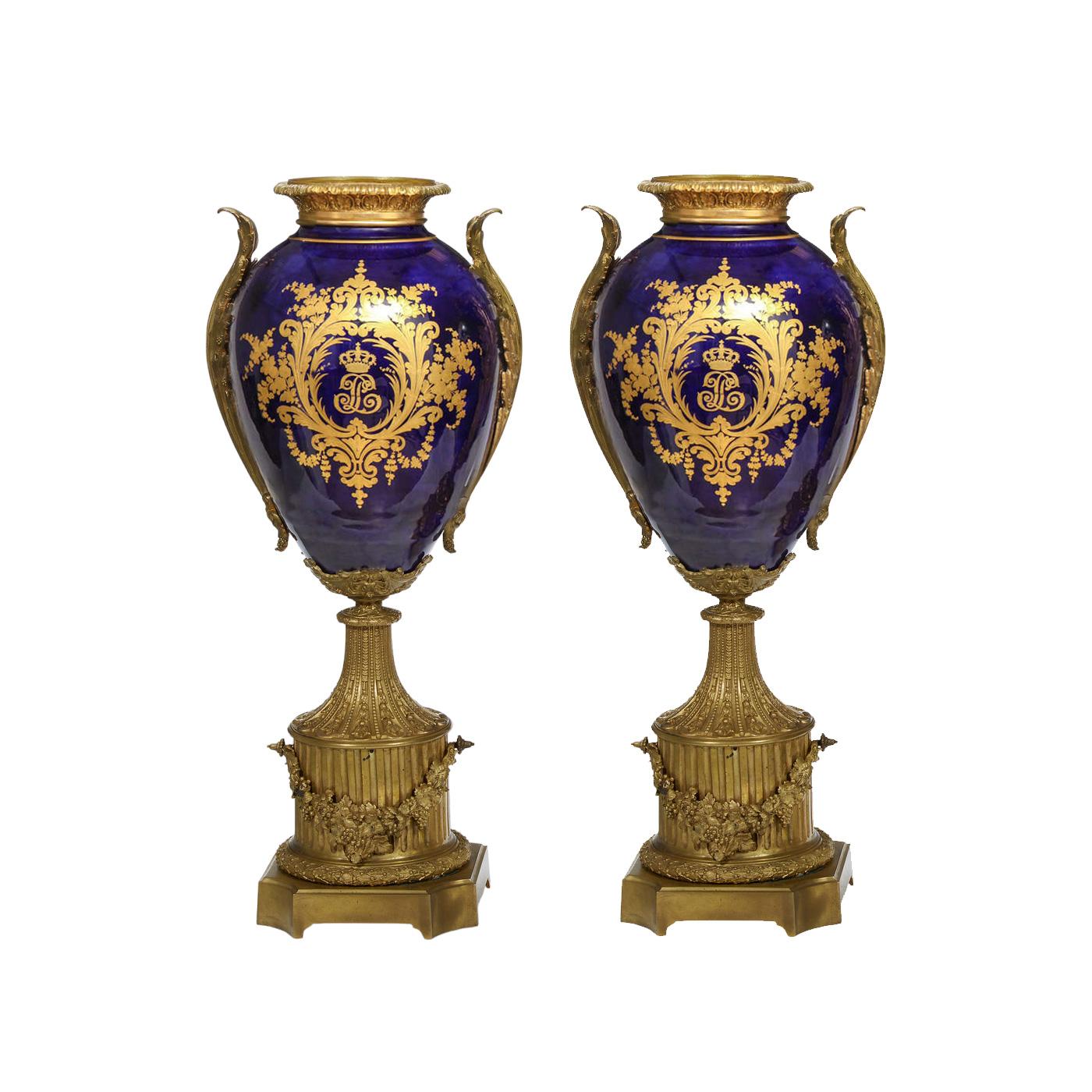 This impressive pair of monumental antique porcelain vases is a testament to the opulence of French craftsmanship in the style reminiscent of Sèvres porcelain, dating back to around 1850. The vases are of a traditional baluster shape. Each vase is