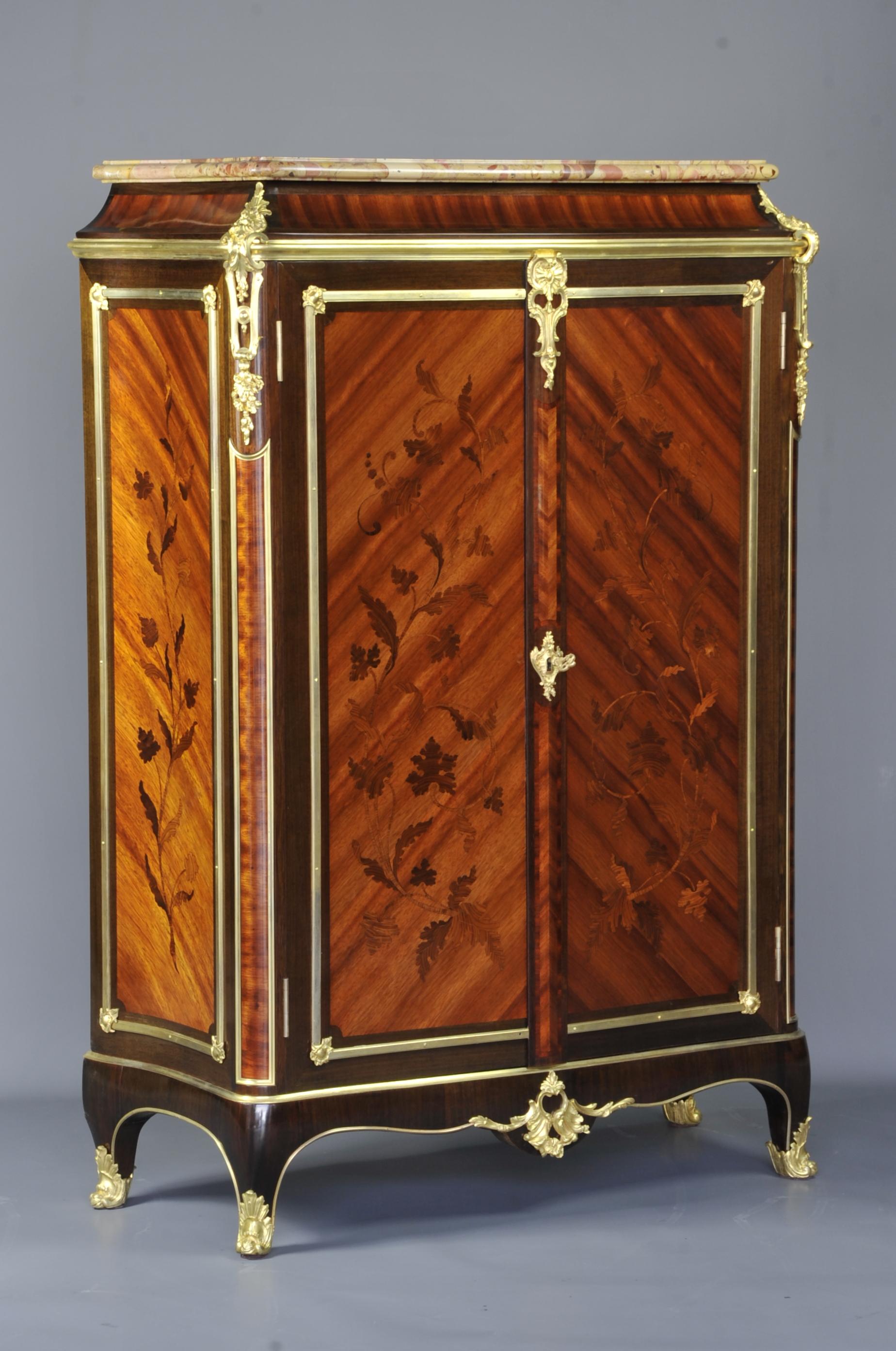 Superb meuble d'appui in tulip wood veneer and amaranth wood in reserve, presenting on the front and on each side beautiful foliage decorations in rosewood marquetry.
The sides are curved and the front, opening with two doors, slightly domed; on