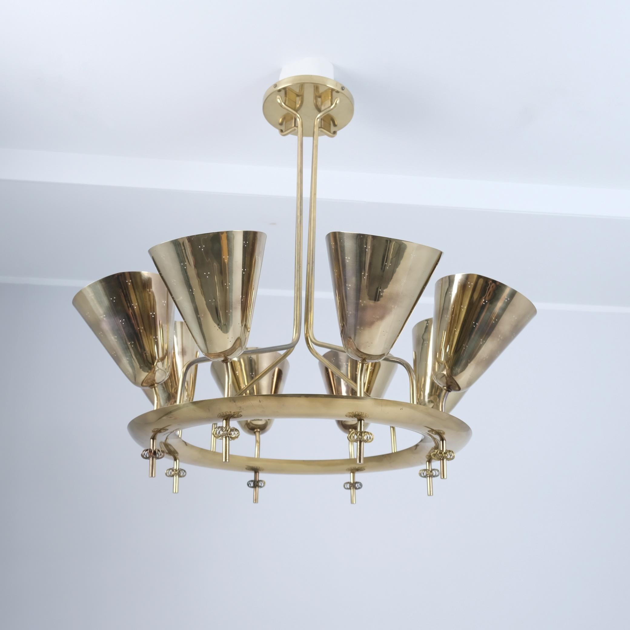 An important chandelier by world renowned Finnish lighting designer Paavo Tynell. This exceptional lamp is built to impress and is made of full brass with eight perforated shades placed on a large ring held by four arms from the middle while still
