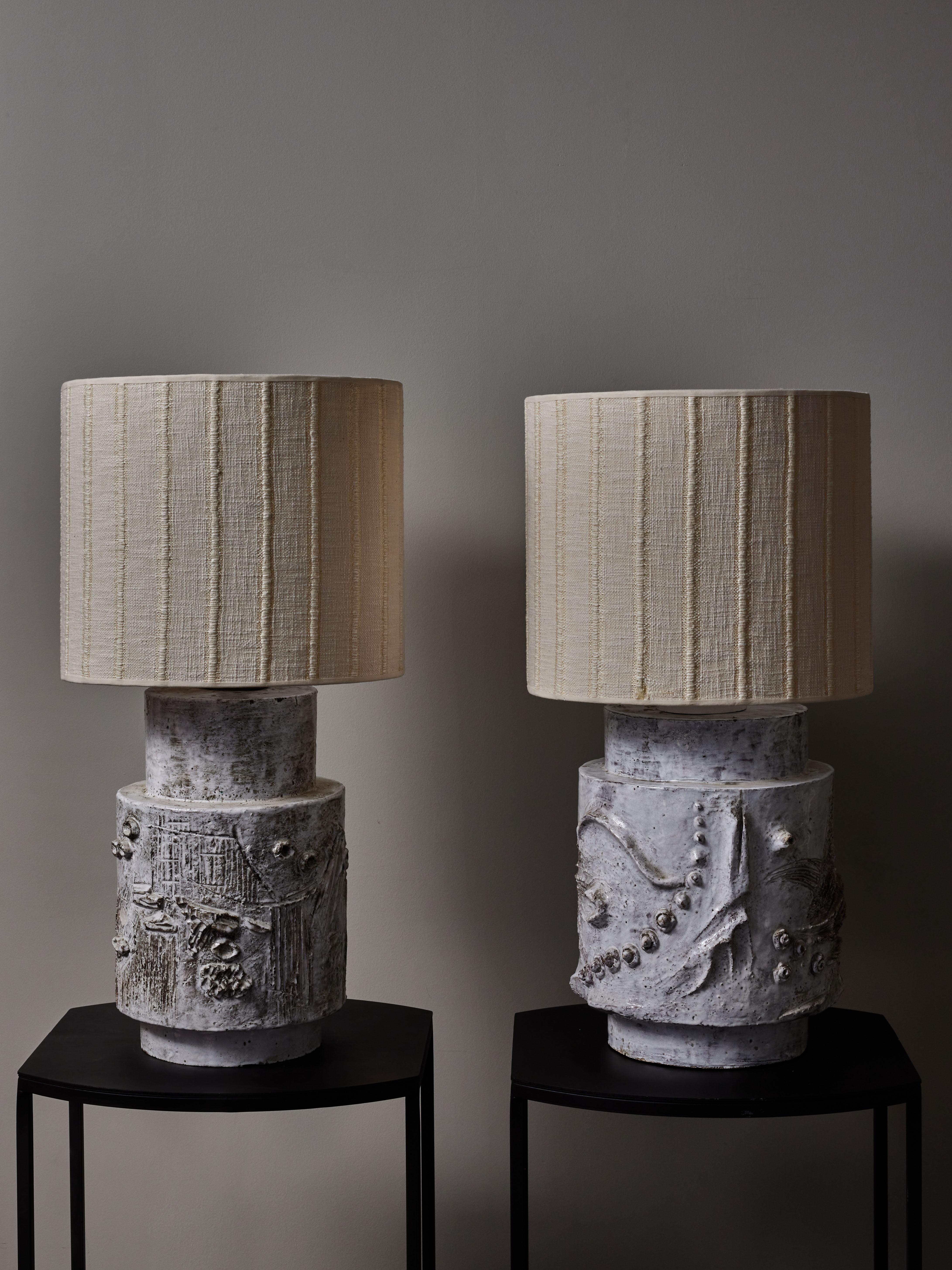 Pair of stunning yet non signed pair of table lamps made of white glazed ceramic.
Despite being slightly different each lamp is covered with different decors and motifs uniformizing the set. 