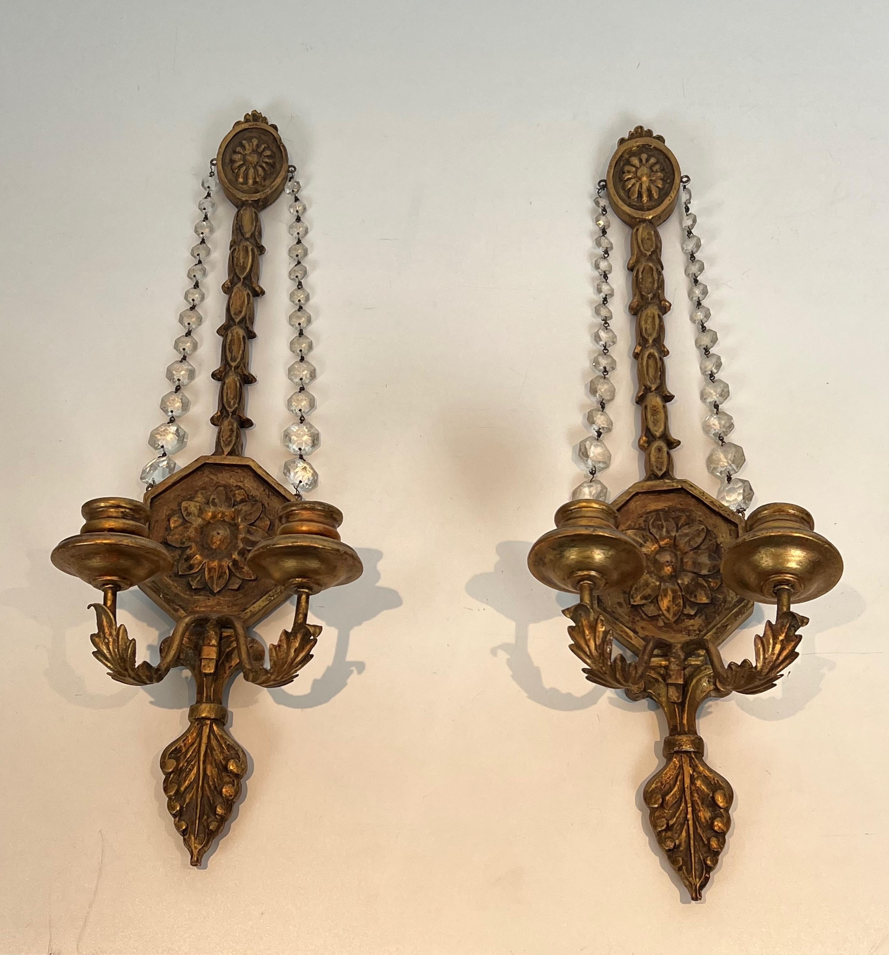 This important pair of Louis the 16th style wall sconces is made of gilded carved wood with crystal garlands. This is a French work. Circa 1940