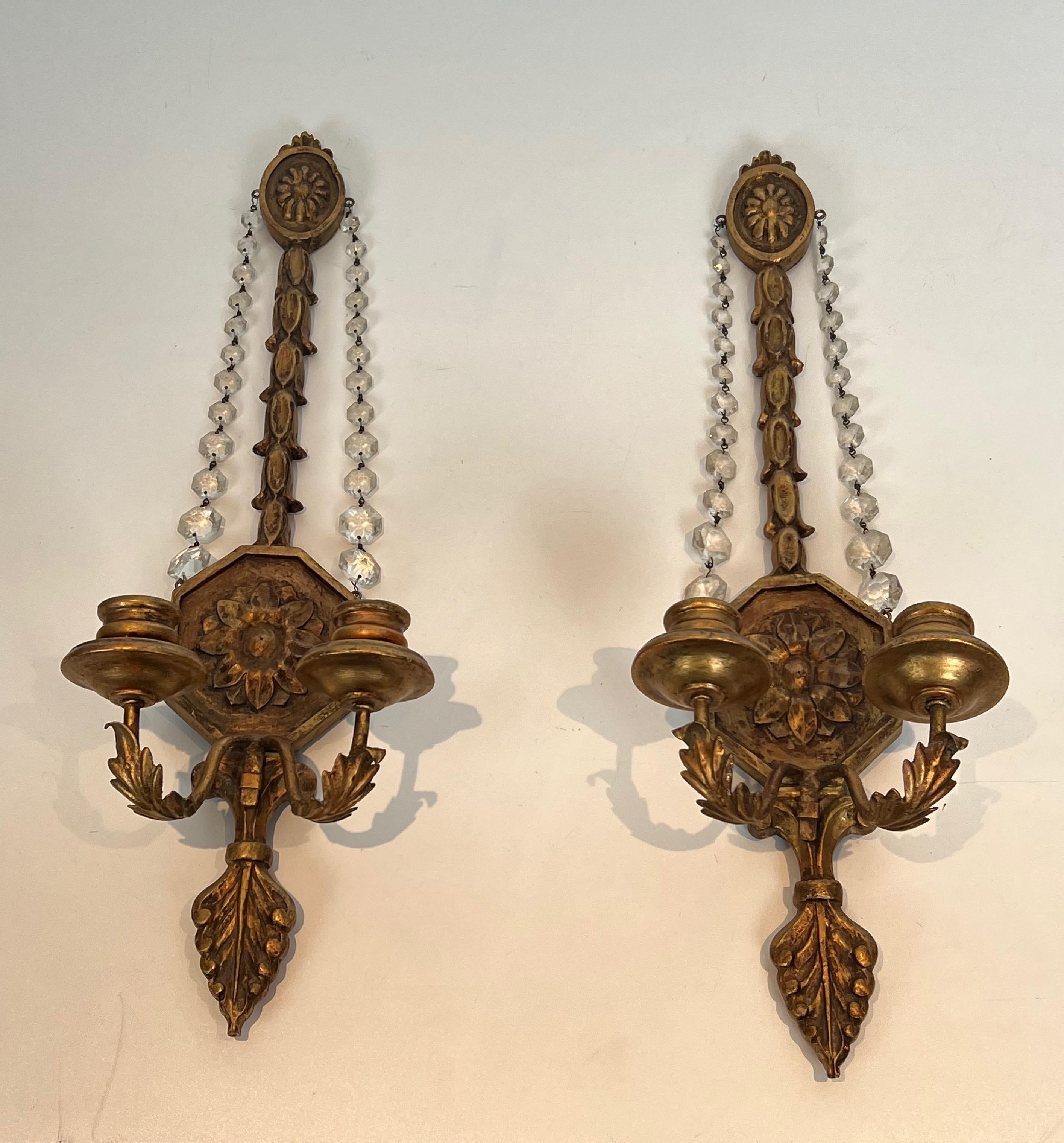 Este importante par de apliques de estilo Luis XVI es de madera tallada dorada con guirnaldas de cristal. Se trata de una obra francesa. Alrededor de 1940