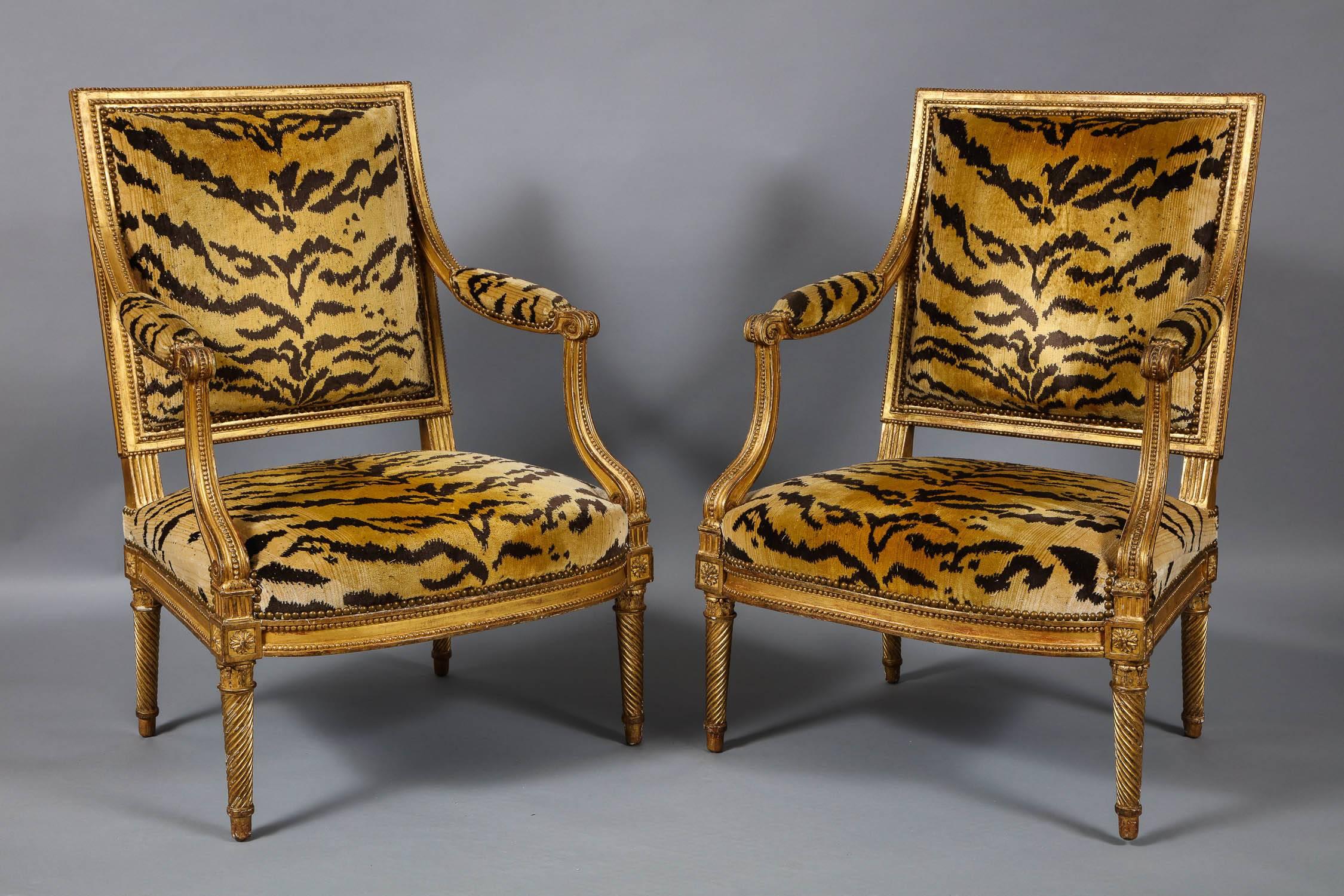 Fine and important pair of 18th century French giltwood open armchairs by Henri Jacob, the square backs with bead carved borders in highly burnished and contrasting matte gilding, the scrolled arms over curved supports, the apron with rounded front