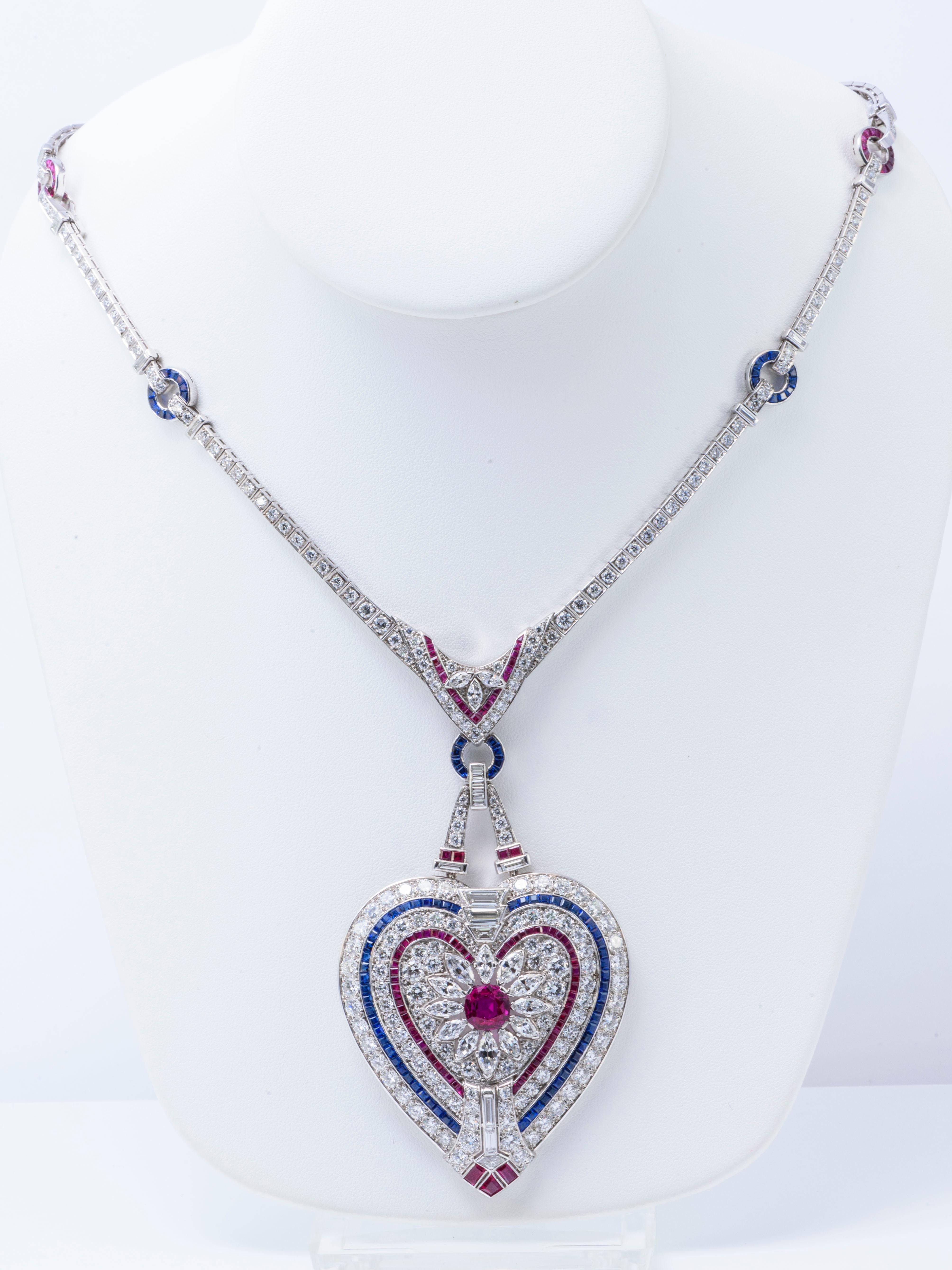 Suspending a variously-cut diamond, calibré-cut ruby and sapphire heart- shaped plaque, centering upon a circular-cut ruby, to the variously-cut diamond neck chain with altering calibré-cut ruby and sapphire links, 18 inches, mounted in platinum. 