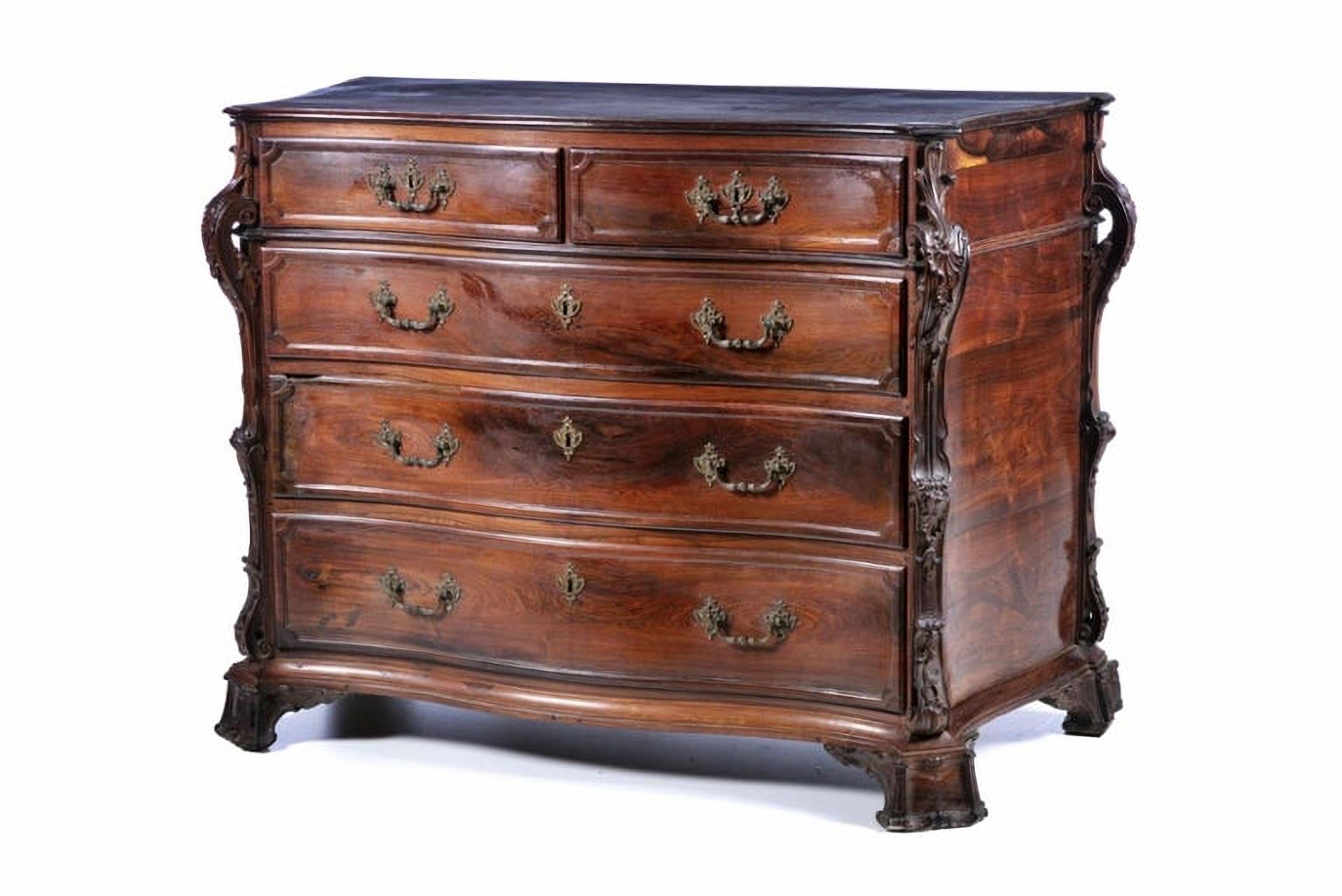 Important Portuguese Commode
18th Century
in carved Brazilian rosewood, with 2 drawers
Wavy body, protruding carved pilasters, decorated with vegetal rolls.
Sits on curved feet ending in curls.
Bronze
Measures: 105cm x 137cm x 65
Very good condition.