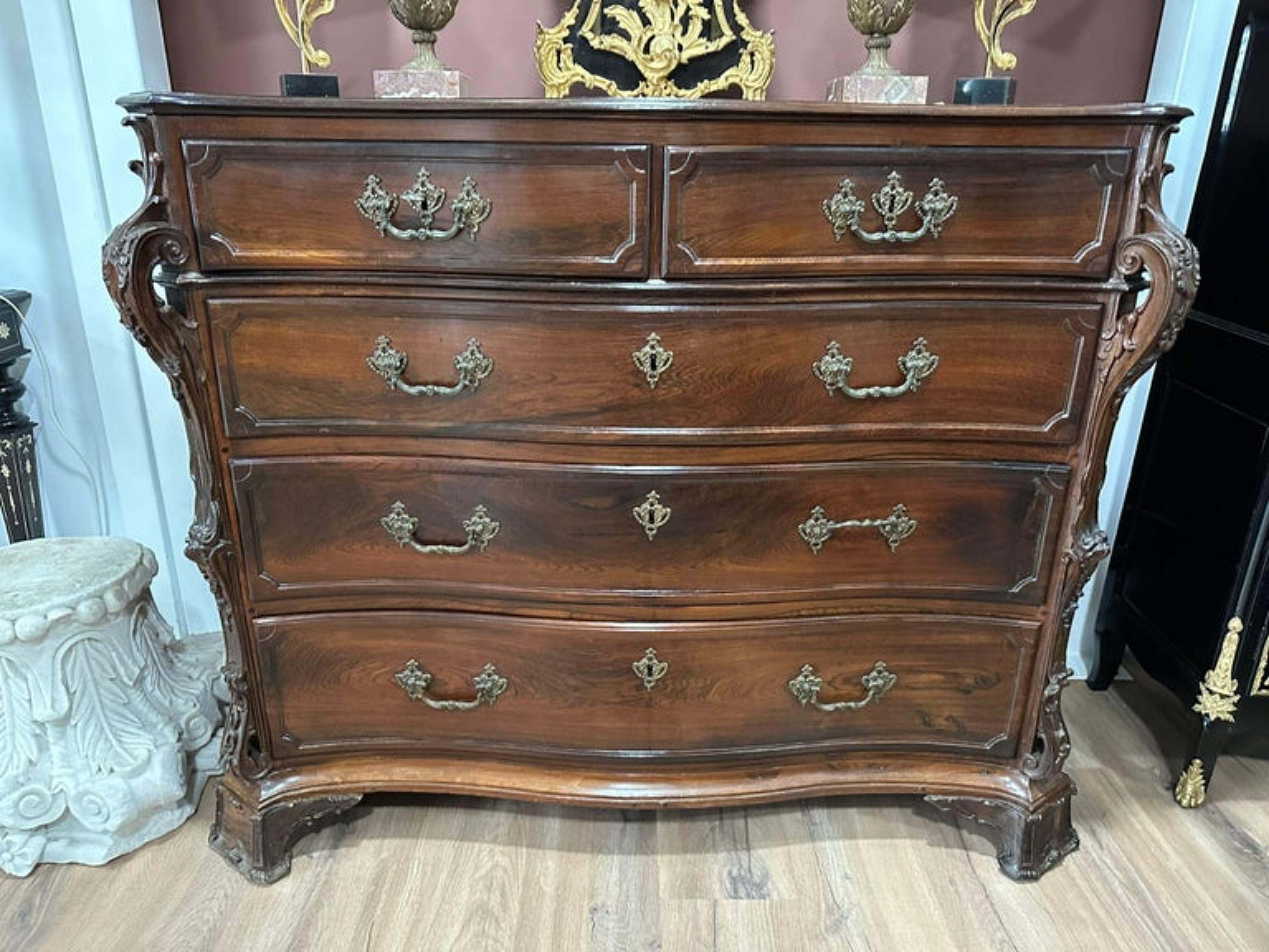 Important Portuguese Commode
18th Century
in carved Brazilian rosewood, with 2 drawers
Wavy body, protruding carved pilasters, decorated with vegetal rolls.
Sits on curved feet ending in curls.
Bronze
Measures: 105cm x 137cm x 65
Very good condition.