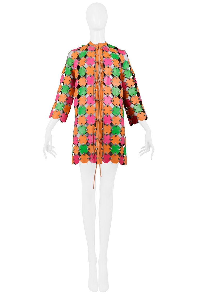 We are pleased to offer an important vintage Paco Rabanne neon pink, orange, and green leather coat dress featuring leather orange ties, silver-tone metal fittings, 3/4 length sleeves, an orange leather placket, and mini-length. A similar piece was