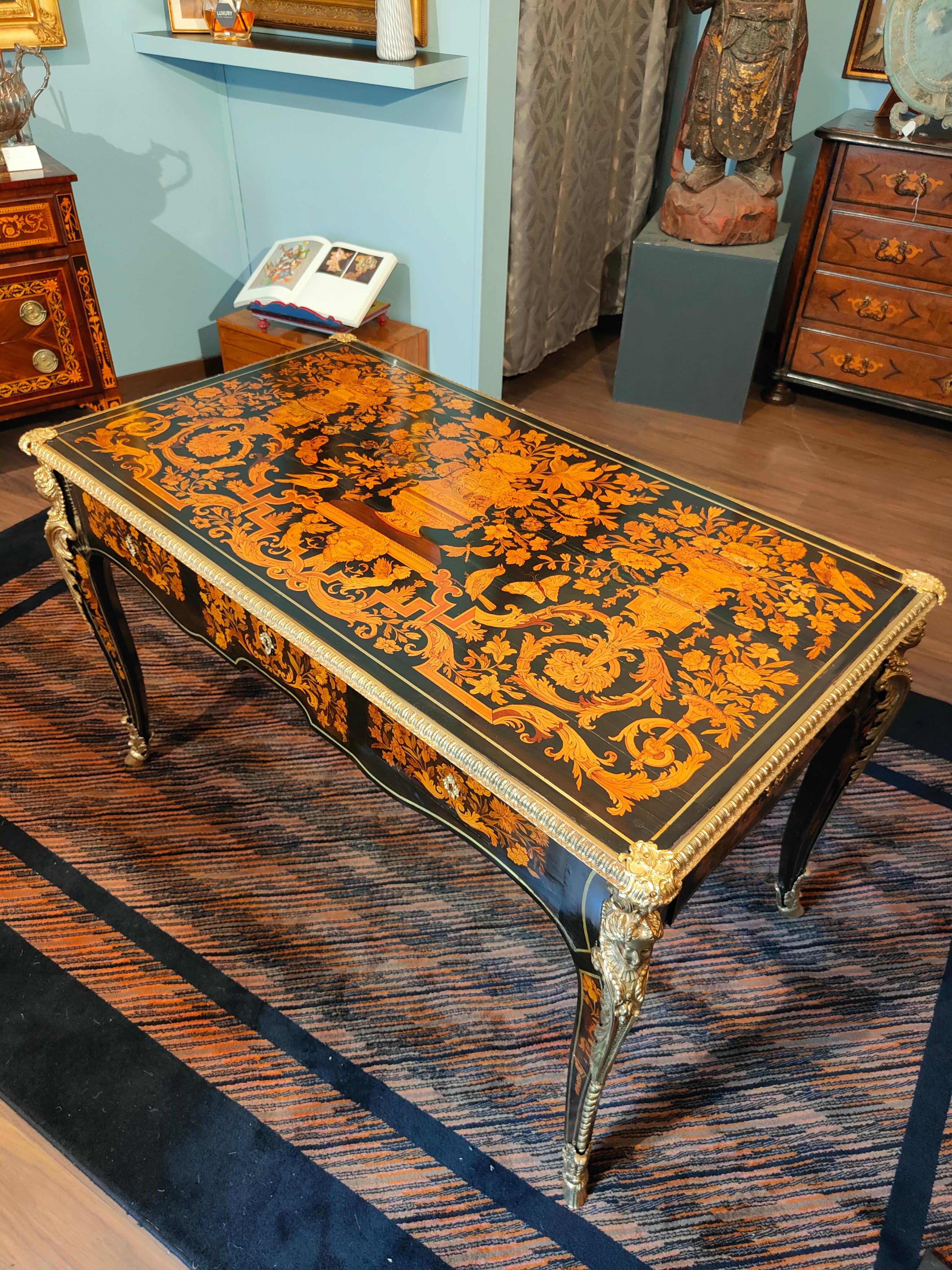 Important rectangular desk table, finely inlaid in various woods.
The table top is made up of several vases with flowers that alternate with floral elements, animals, butterflies and birds. The different floral and geometric shapes are then